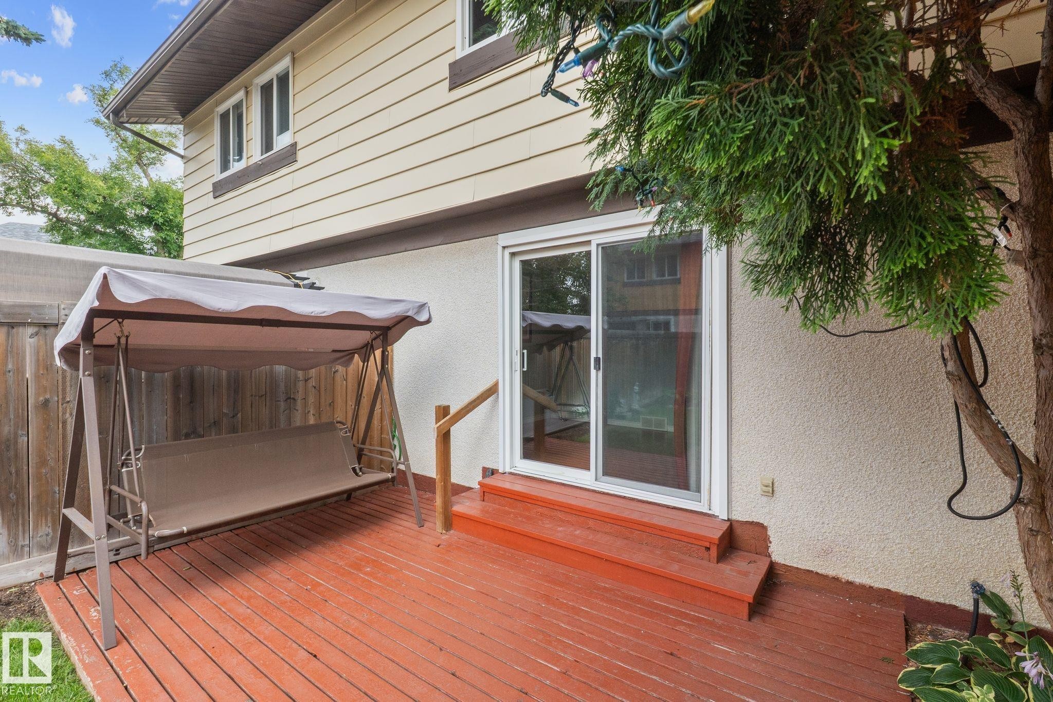 Rear wood-finish decking with stairs, sliding glass door, and stucco exterior - 152 Woodstock Nw, Edmonton, AB - Outdoor With Deck Patio Veranda With Exterior