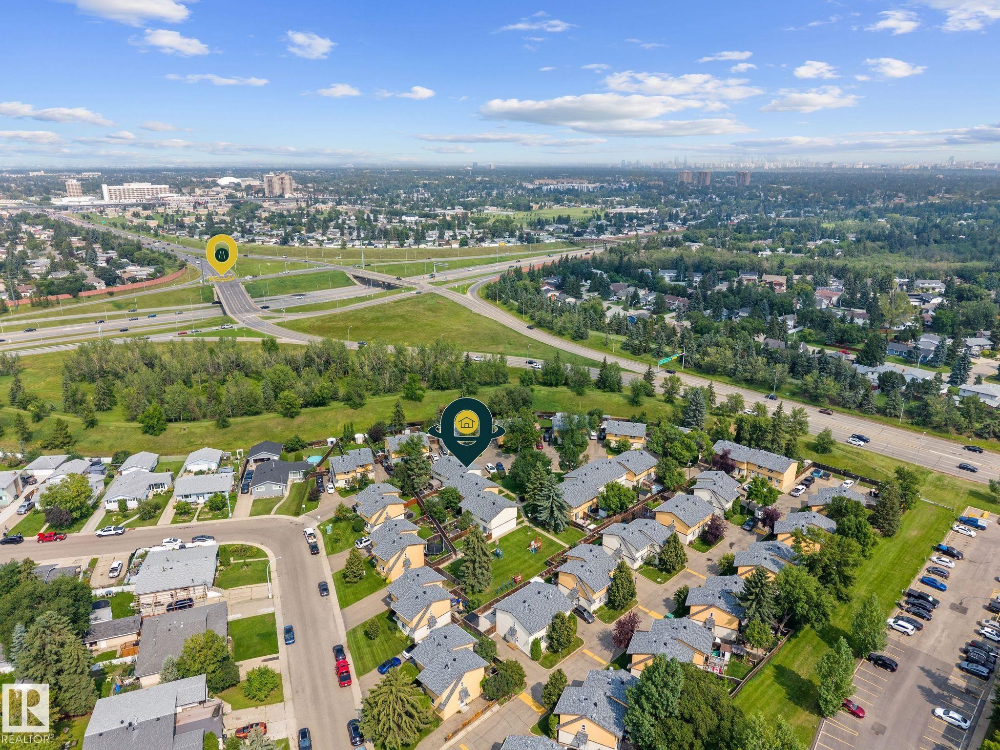 Aerial perspective showcasing a residential development with individual units, surrounding green spaces, and vehicular thoroughfares - 152 Woodstock Nw, Edmonton, AB - Outdoor With View