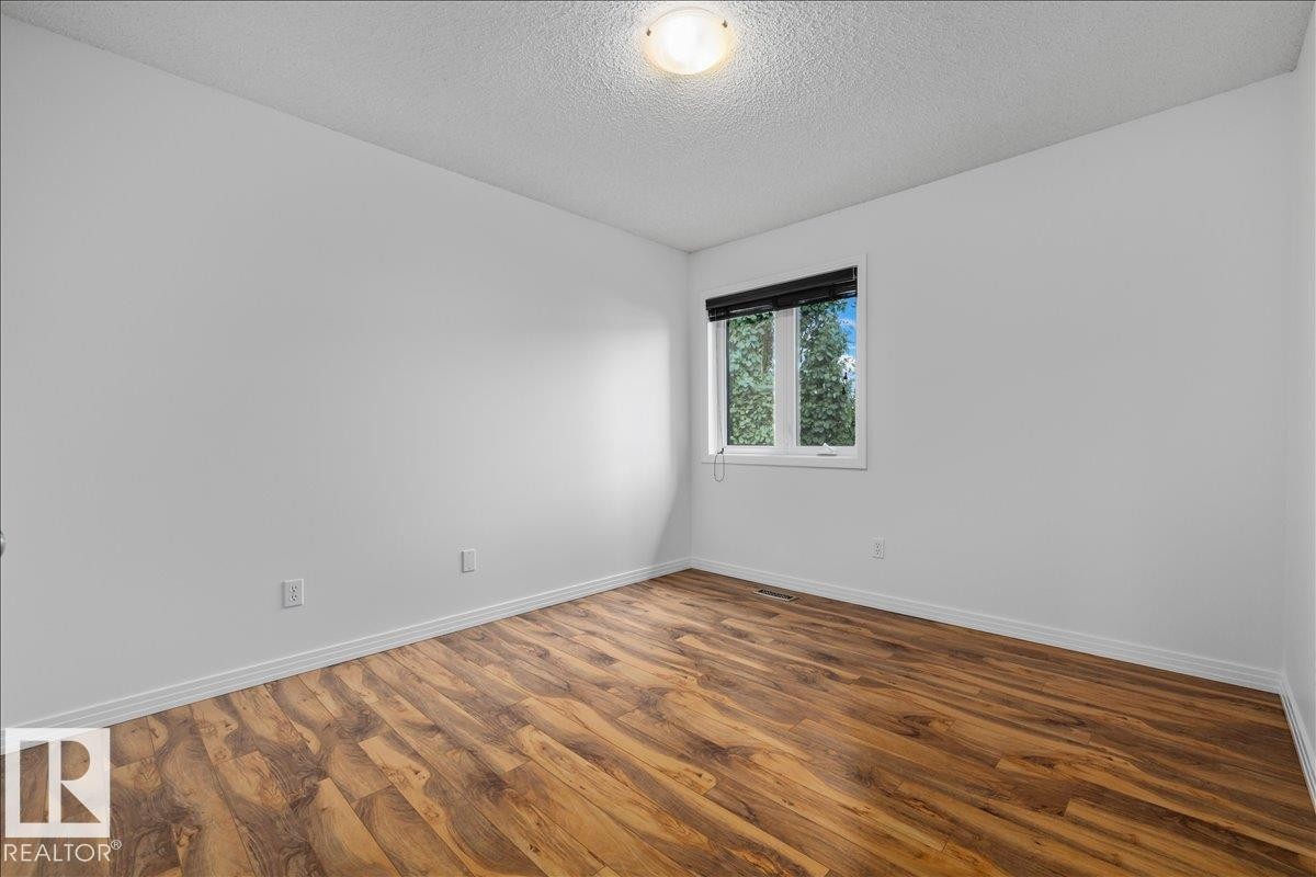 Room featuring wood-finish flooring, white baseboards, a white window frame, and a ceiling-mounted light fixture - 1086 Grantham Drive Nw, Edmonton, AB - Indoor Photo Showing Other Room