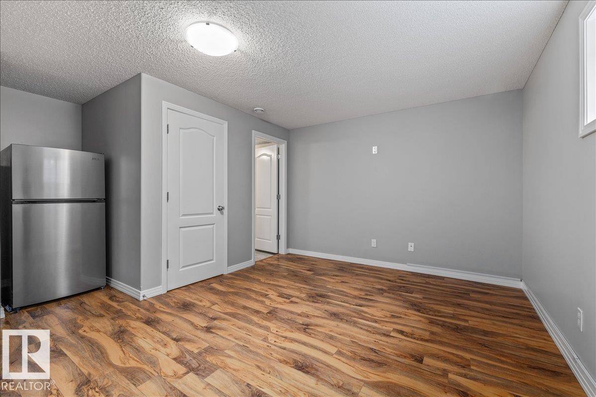 Spacious room featuring wood-finish flooring, light gray walls, and white trim - 1086 Grantham Drive Nw, Edmonton, AB - Indoor Photo Showing Other Room