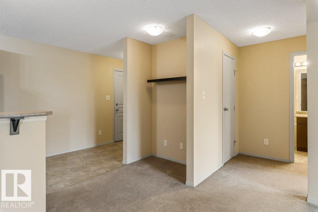Wall-to-wall carpeting, overhead flush-mount lighting, and neutral wall tones - #307 1188 Hyndman Rd Nw, Edmonton, AB - Indoor Photo Showing Other Room