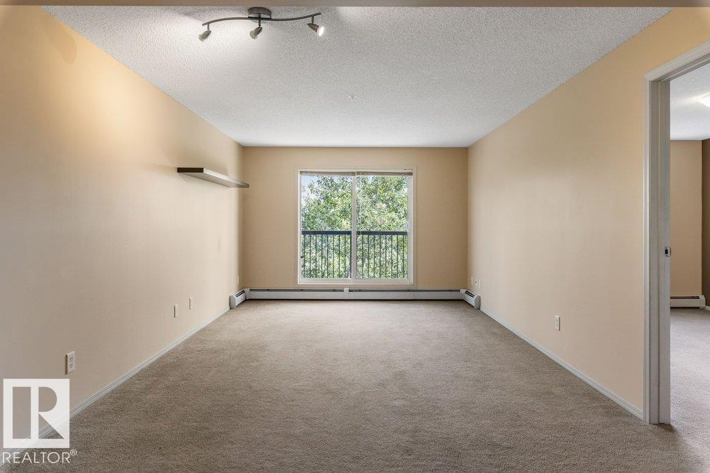 Neutral-toned carpeting throughout - #307 1188 Hyndman Rd Nw, Edmonton, AB - Indoor Photo Showing Other Room
