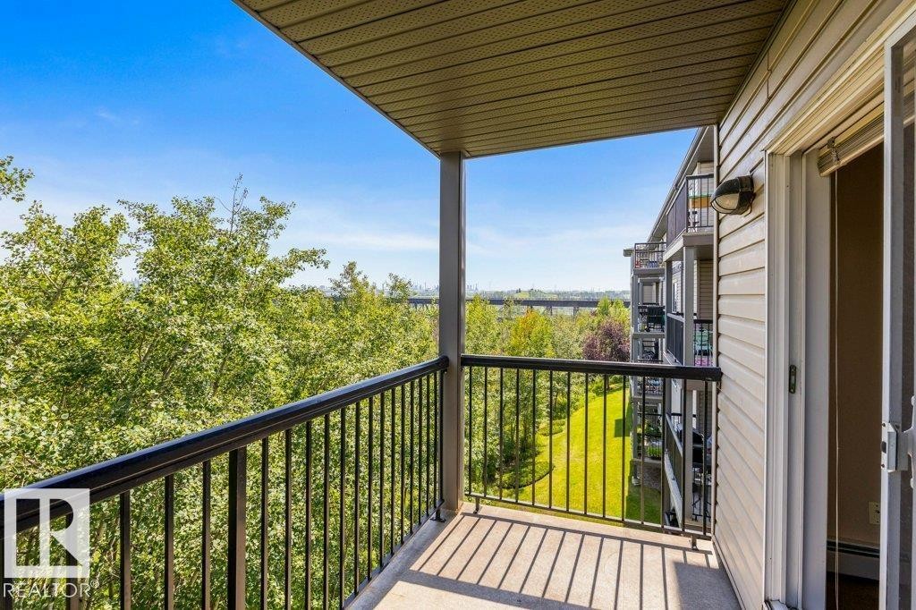 Private balcony with dark metal railing, durable concrete flooring, and a sliding glass door entry - #307 1188 Hyndman Rd Nw, Edmonton, AB - Outdoor With Balcony With Exterior