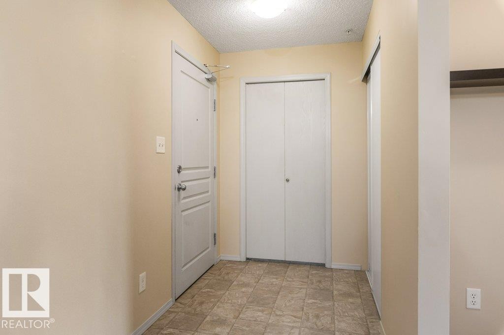 Tile flooring, flush mount lighting, white paneled doors, and a built-in storage niche - #307 1188 Hyndman Rd Nw, Edmonton, AB - Indoor Photo Showing Other Room