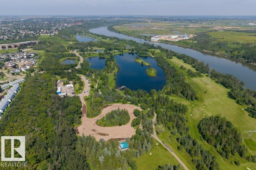 Meandering river, multiple lakes, extensive green spaces, mature tree cover, and residential areas in the background - #307 1188 Hyndman Rd Nw, Edmonton, AB - Outdoor With Body Of Water With View