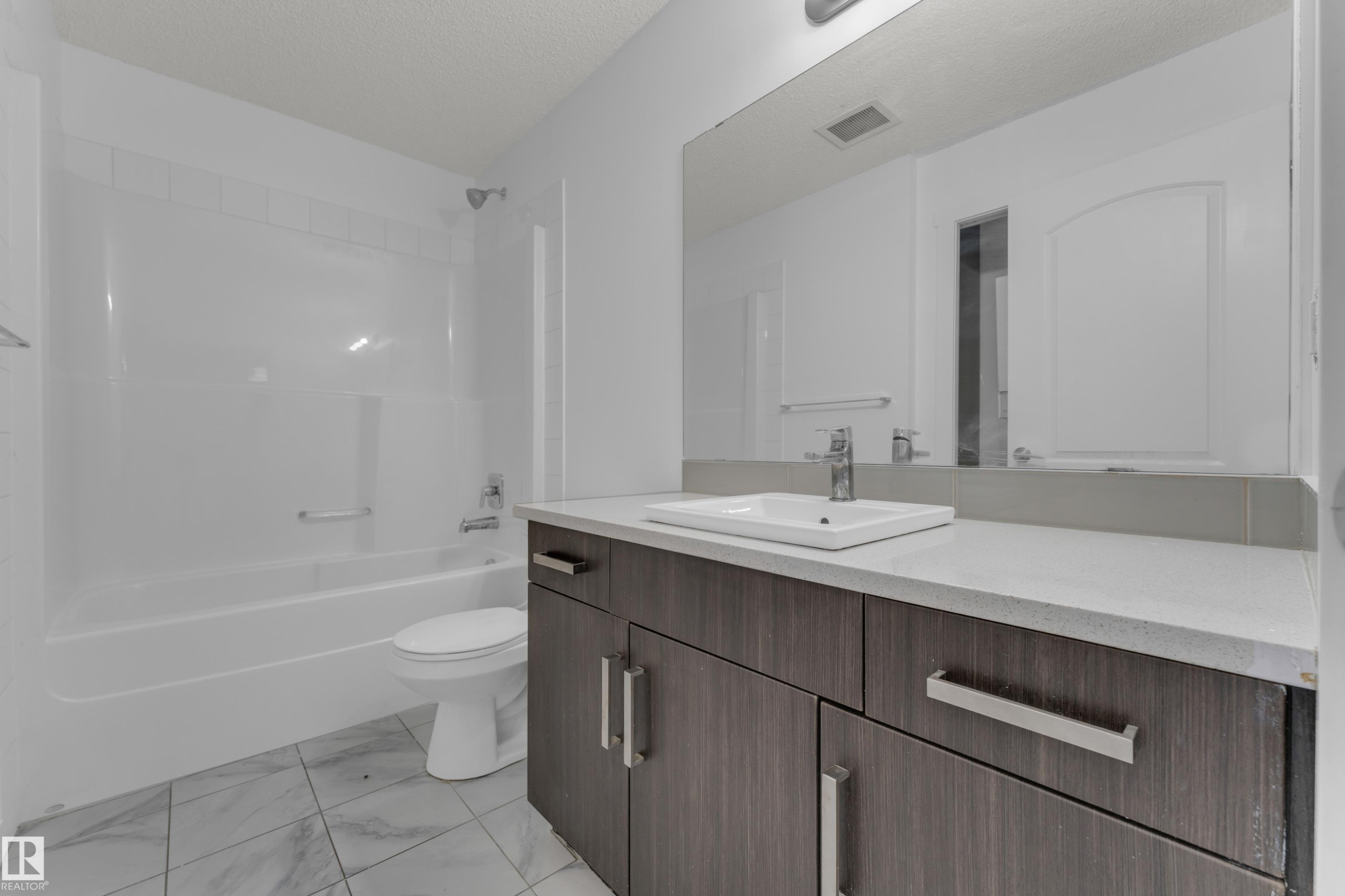 Wood-finish vanity with a rectangular undermount sink, light-toned countertop, and integrated mirror - #217 667 Watt Bv Sw, Edmonton, AB - Indoor Photo Showing Bathroom