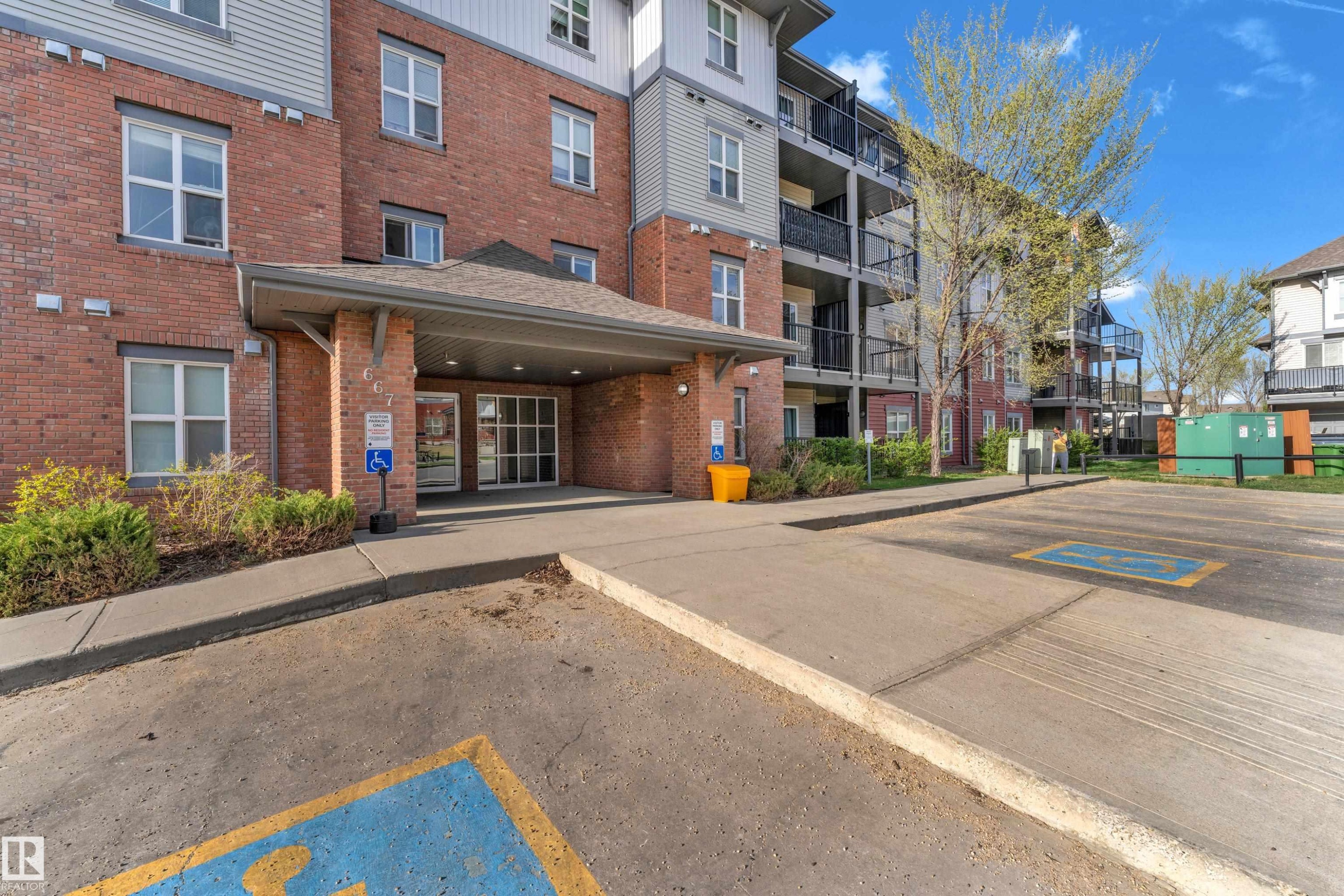 Multi-story building featuring brick and siding exterior, covered entry with glass doors, and multiple private balconies - #217 667 Watt Bv Sw, Edmonton, AB - Outdoor With Balcony