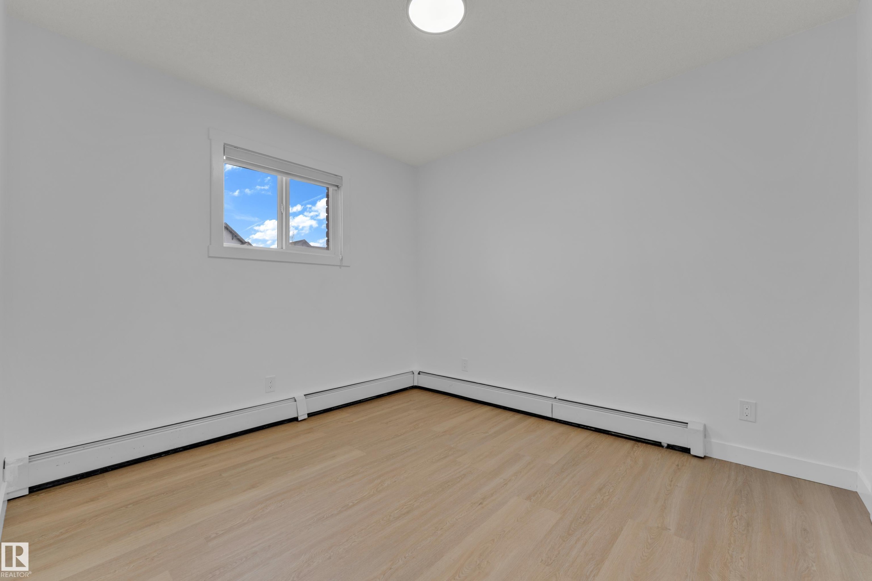 Recessed ceiling light, light wood-finish flooring, white walls, and a window with a roller shade - #217 667 Watt Bv Sw, Edmonton, AB - Indoor Photo Showing Other Room