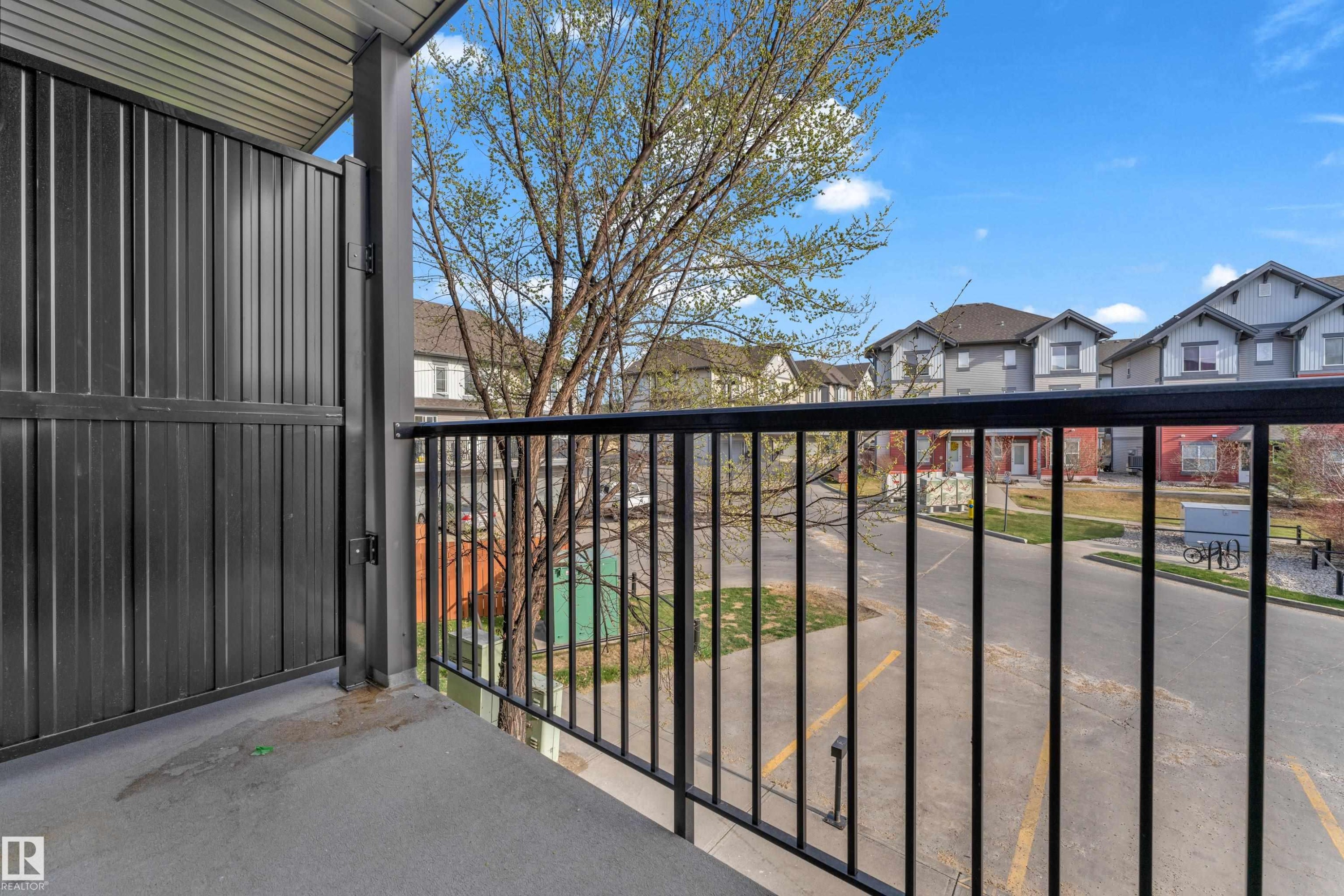 Balcony with black metal railing and privacy screen, concrete flooring, and a corrugated metal ceiling - #217 667 Watt Bv Sw, Edmonton, AB - Outdoor With Balcony