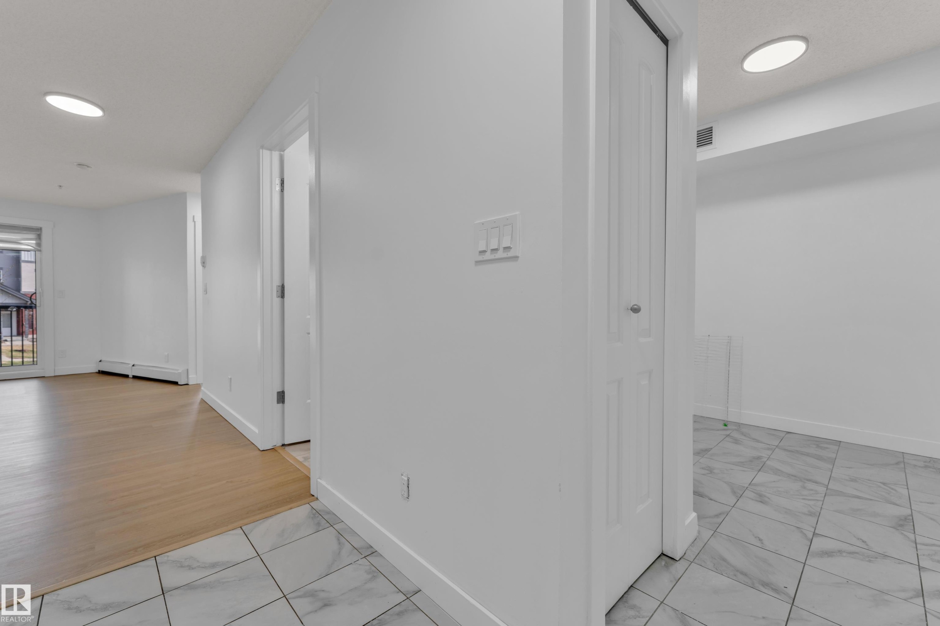 Recessed ceiling lighting, white walls, wood-finish flooring, and white tile flooring - #217 667 Watt Bv Sw, Edmonton, AB - Indoor Photo Showing Other Room