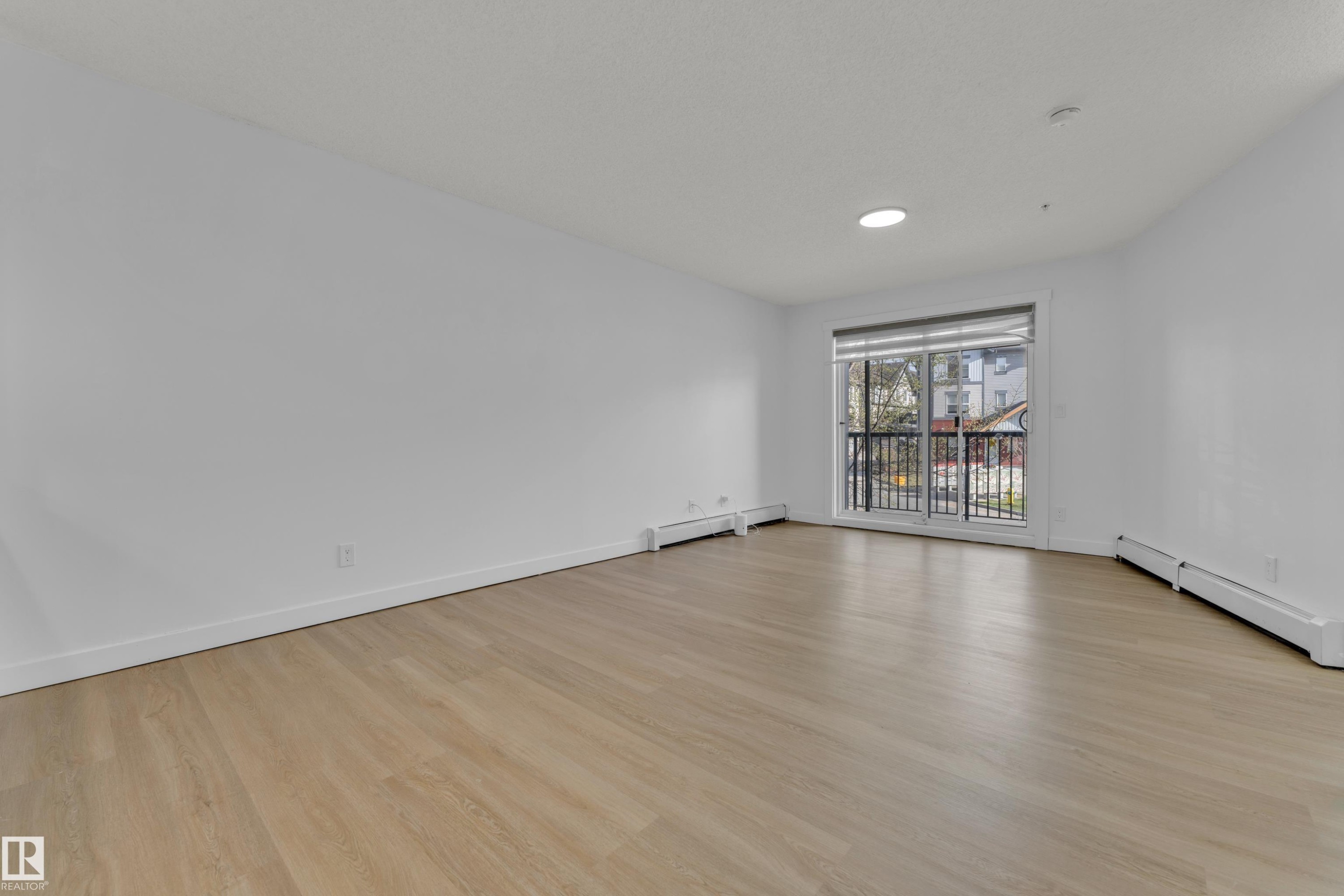 Wood-finish flooring with white walls and a sliding glass door - #217 667 Watt Bv Sw, Edmonton, AB - Indoor