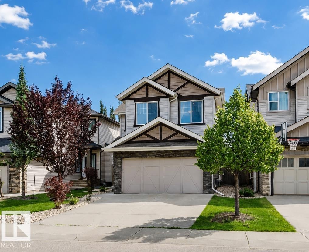 Two-story residence featuring light-colored siding, a prominent two-car garage, and stone facade accents - 15839 10 Avenue Sw, Edmonton, AB - Outdoor With Facade