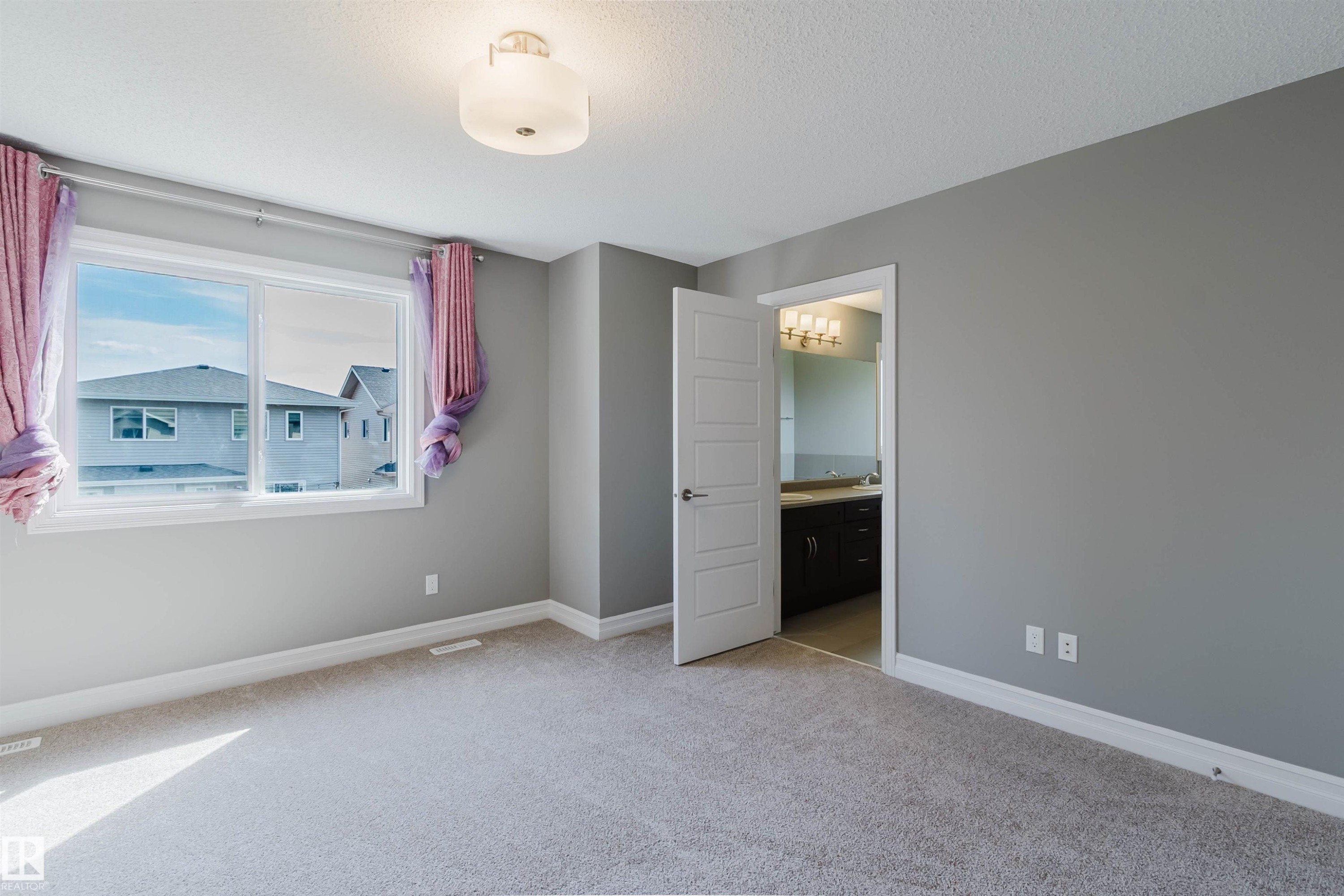 Neutral gray wall paint, plush carpeting, a multi-pane window, and a flush-mount ceiling light fixture - 15839 10 Avenue Sw, Edmonton, AB - Indoor