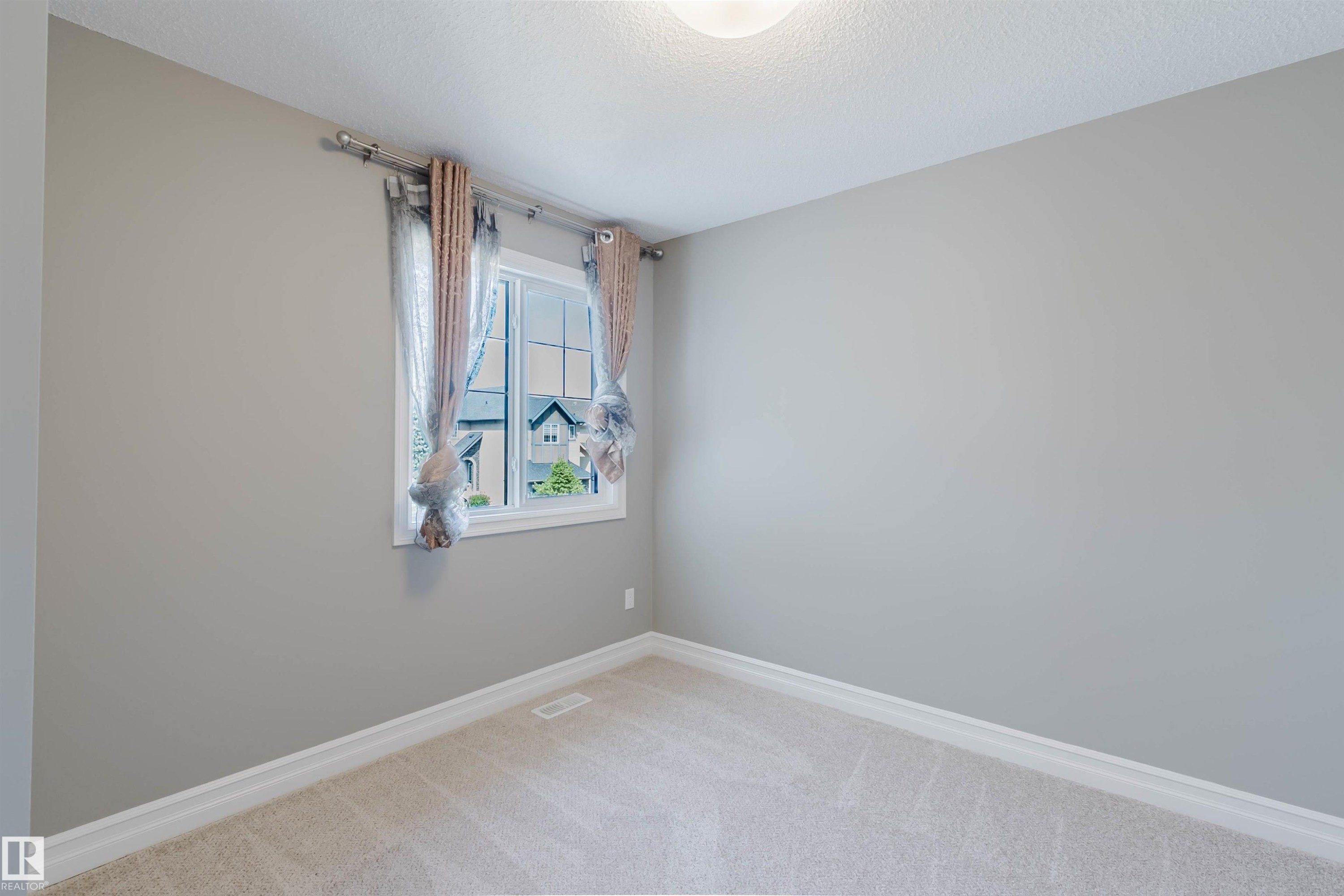 Neutral wall paint, carpet flooring, window with white trim, and ceiling light fixture - 15839 10 Avenue Sw, Edmonton, AB - Indoor Photo Showing Other Room