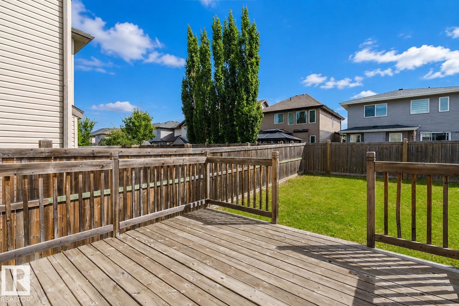 Expansive wood deck with a perimeter railing, accessing a grassy yard, and surrounded by wood fencing - 15839 10 Avenue Sw, Edmonton, AB - Outdoor With Deck Patio Veranda With Exterior