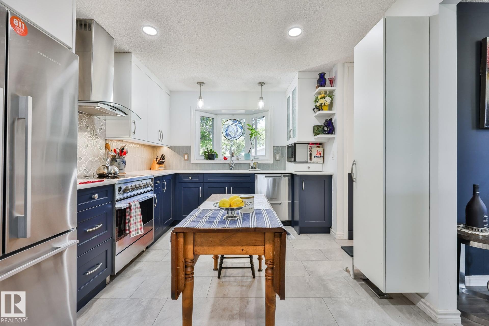 Kitchen featuring two-tone cabinetry, stainless steel appliances, mosaic tile backsplash, recessed lighting, and a bay window - 8932 187 Street Nw, Edmonton, AB - Indoor Photo Showing Kitchen With Upgraded Kitchen