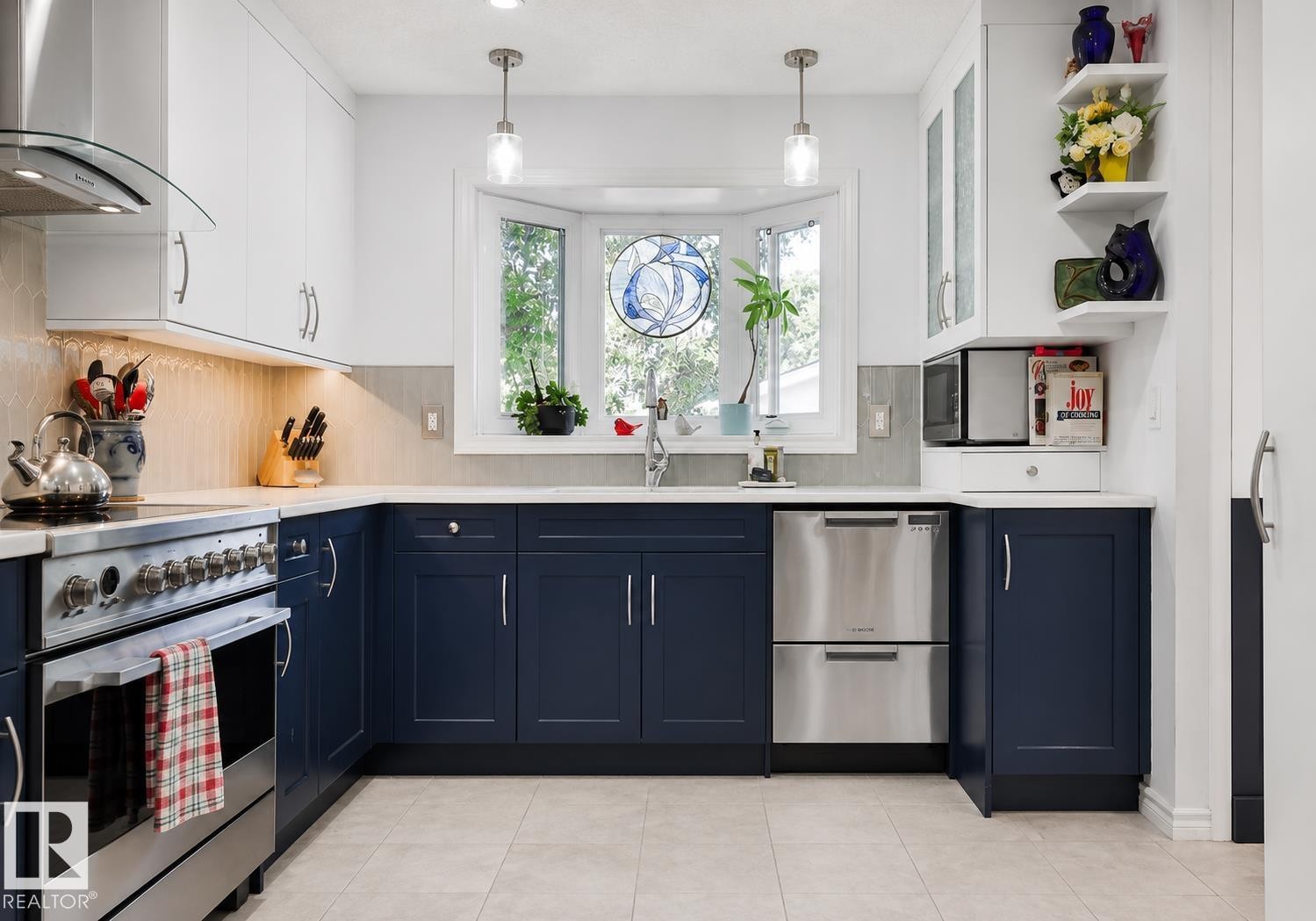 Kitchen featuring two-tone cabinetry with stainless steel hardware, a stainless steel range with overhead hood, a stainless steel dishwasher, and a bay window - 8932 187 Street Nw, Edmonton, AB - Indoor Photo Showing Kitchen With Upgraded Kitchen