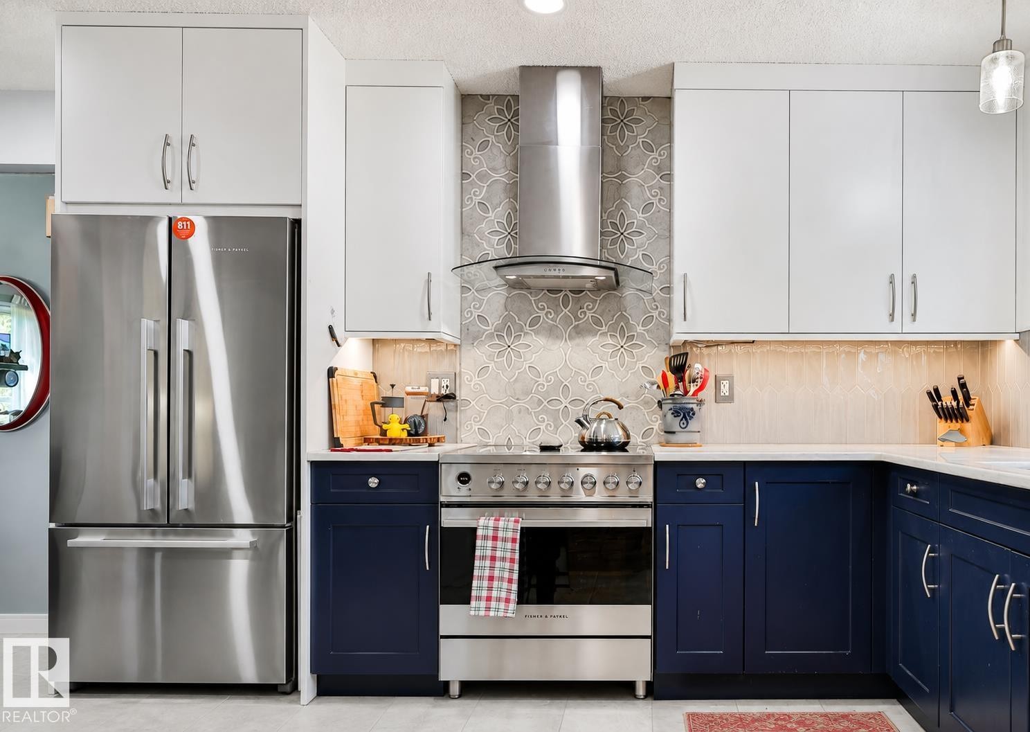 Stainless steel appliances, white upper cabinetry, blue lower cabinetry, white countertops, and a decorative tile backsplash - 8932 187 Street Nw, Edmonton, AB - Indoor Photo Showing Kitchen With Upgraded Kitchen