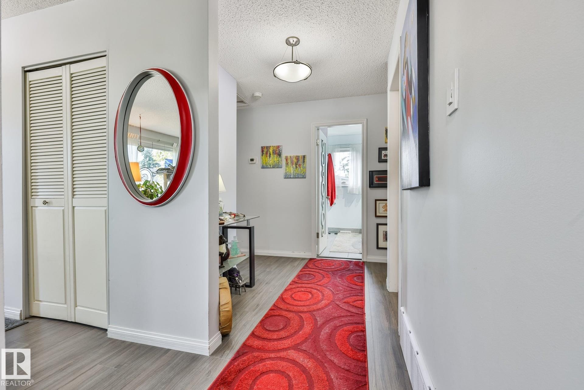 Light gray wall paint, wood-finish flooring, louvered bi-fold doors, and a ceiling-mounted light fixture - 8932 187 Street Nw, Edmonton, AB - Indoor Photo Showing Other Room