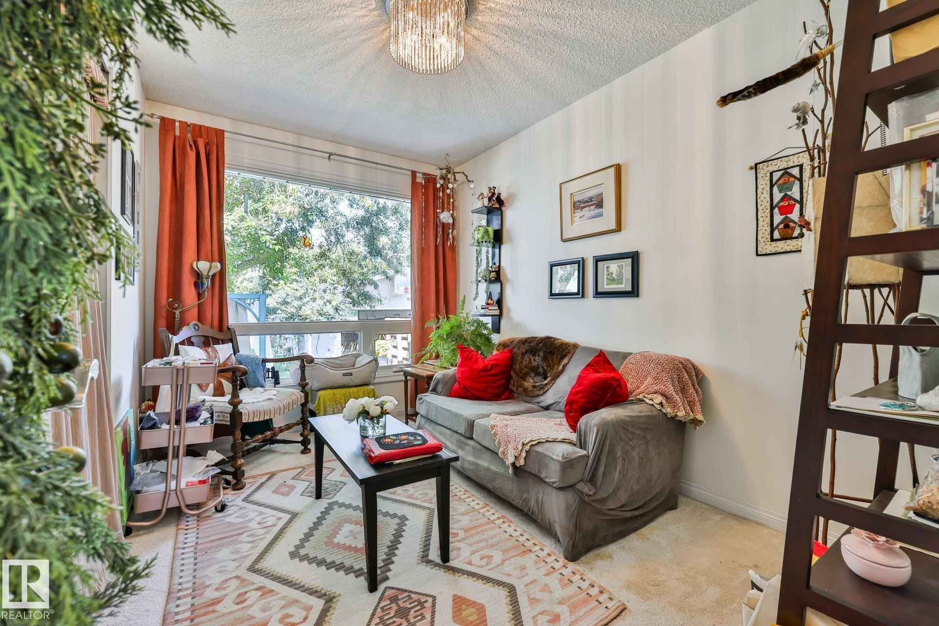 Bright living room bathed in natural light through expansive windows with orange drapery - 8932 187 Street Nw, Edmonton, AB - Indoor Photo Showing Living Room