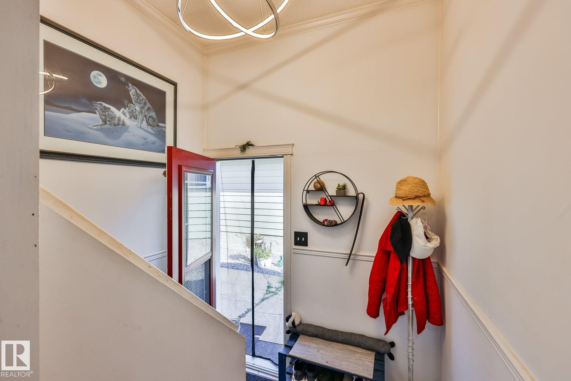 Red entry door with glass paneling, crown molding, and a modern ceiling light fixture - 8932 187 Street Nw, Edmonton, AB - Indoor Photo Showing Other Room