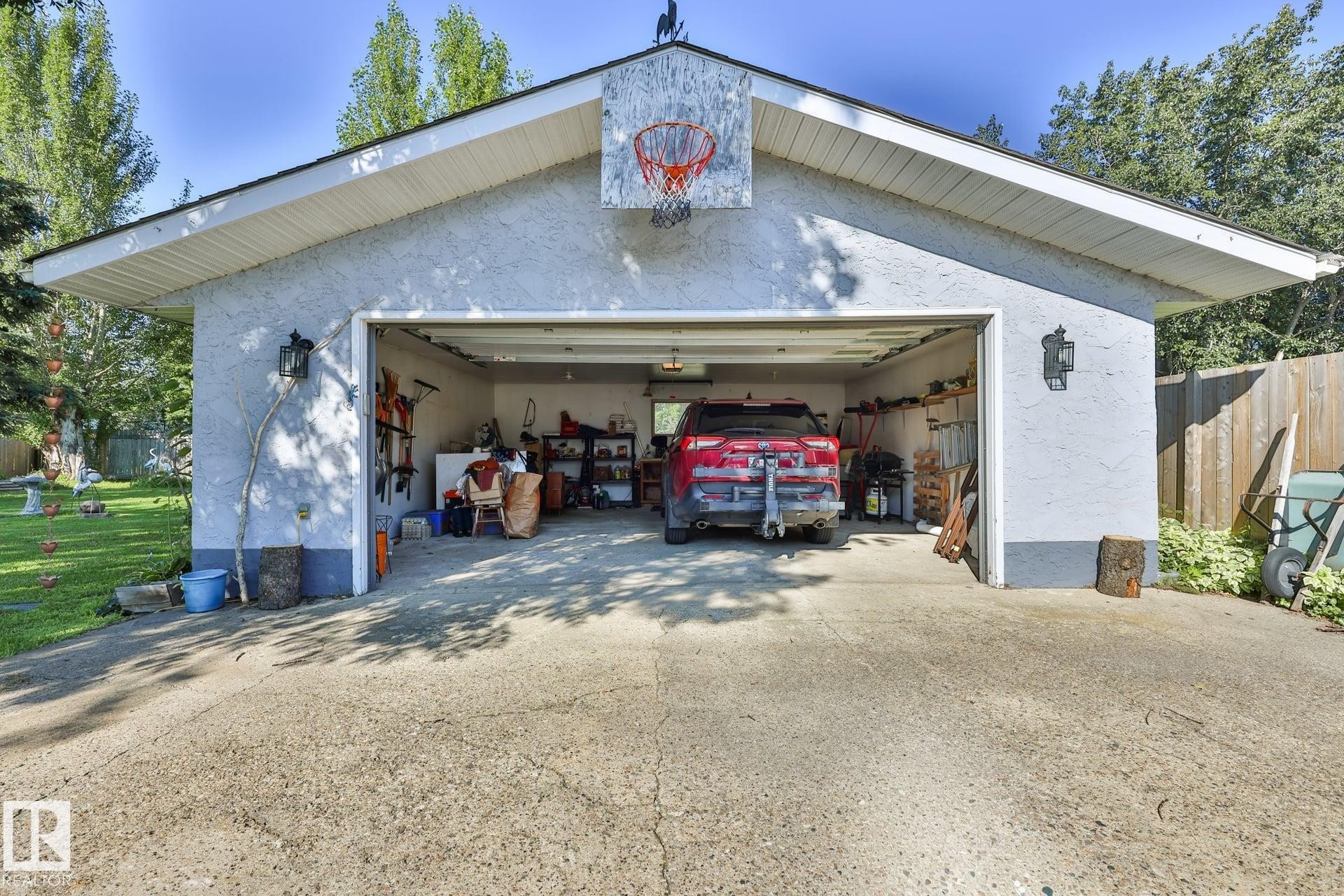 Detached garage featuring a stucco exterior, concrete driveway, and a basketball hoop - 8932 187 Street Nw, Edmonton, AB - Outdoor