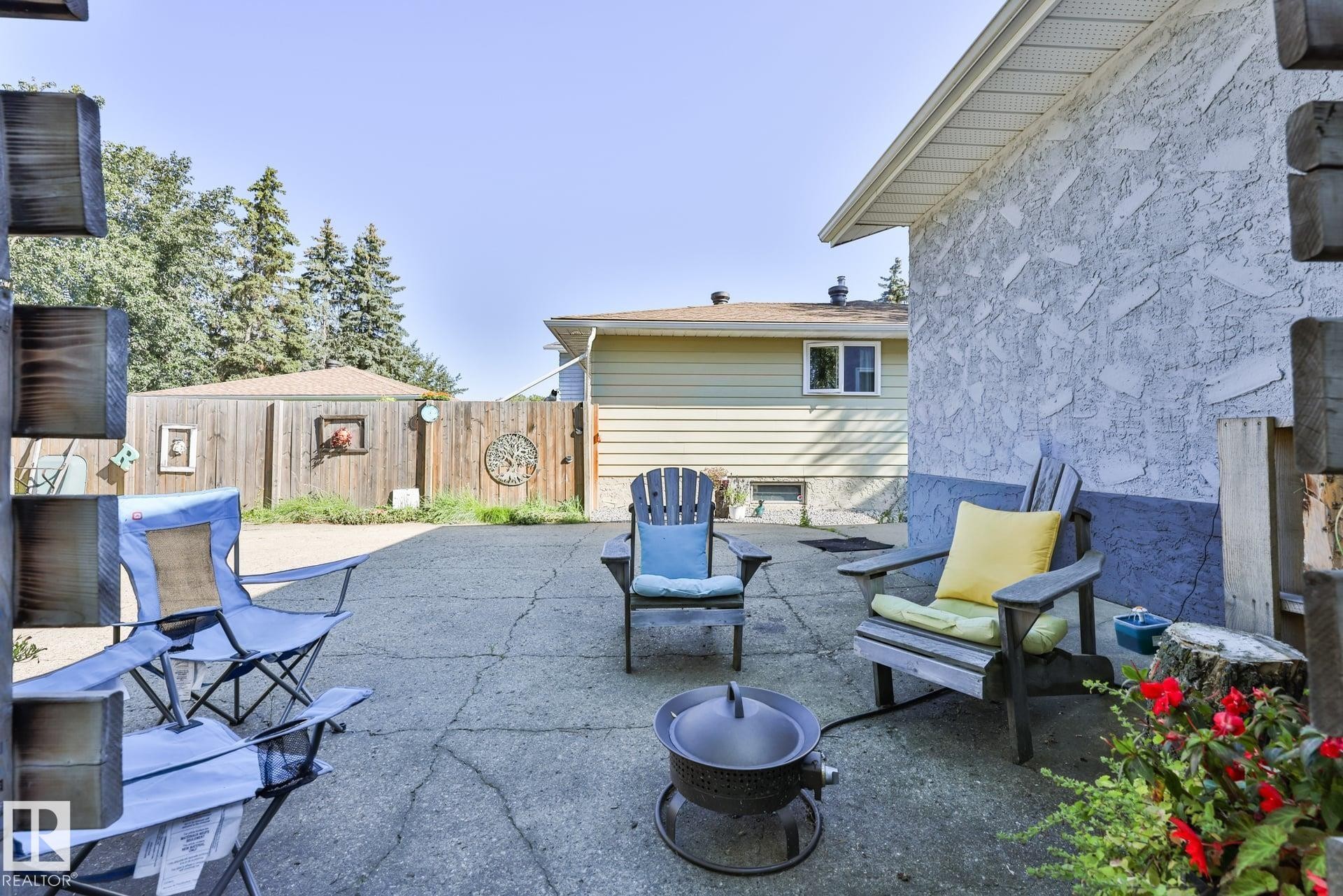 Exterior stucco siding with a lower painted accent, concrete patio, and wood privacy fencing - 8932 187 Street Nw, Edmonton, AB - Outdoor With Exterior
