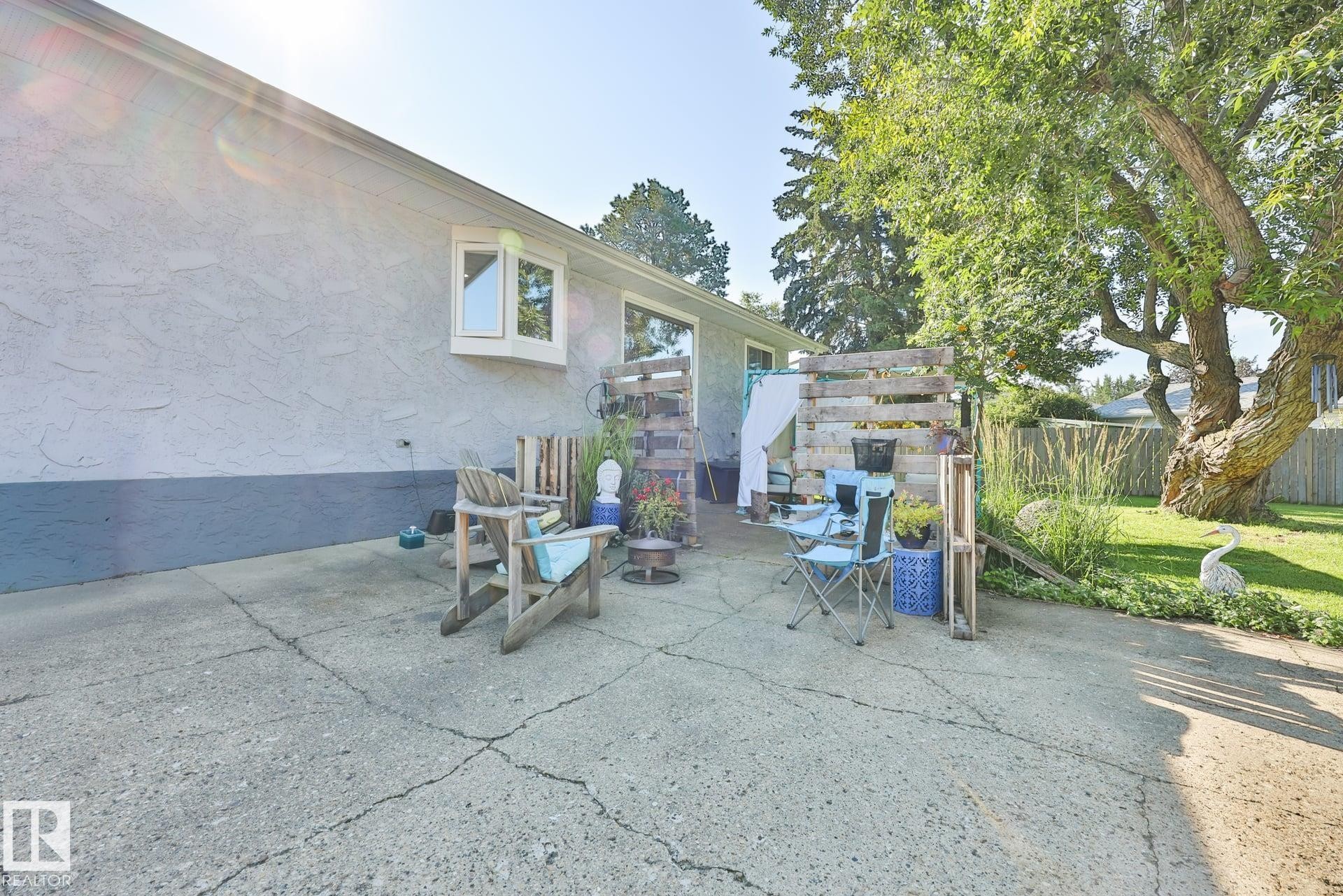 Concrete patio area with a bay window and stucco exterior - 8932 187 Street Nw, Edmonton, AB - Outdoor