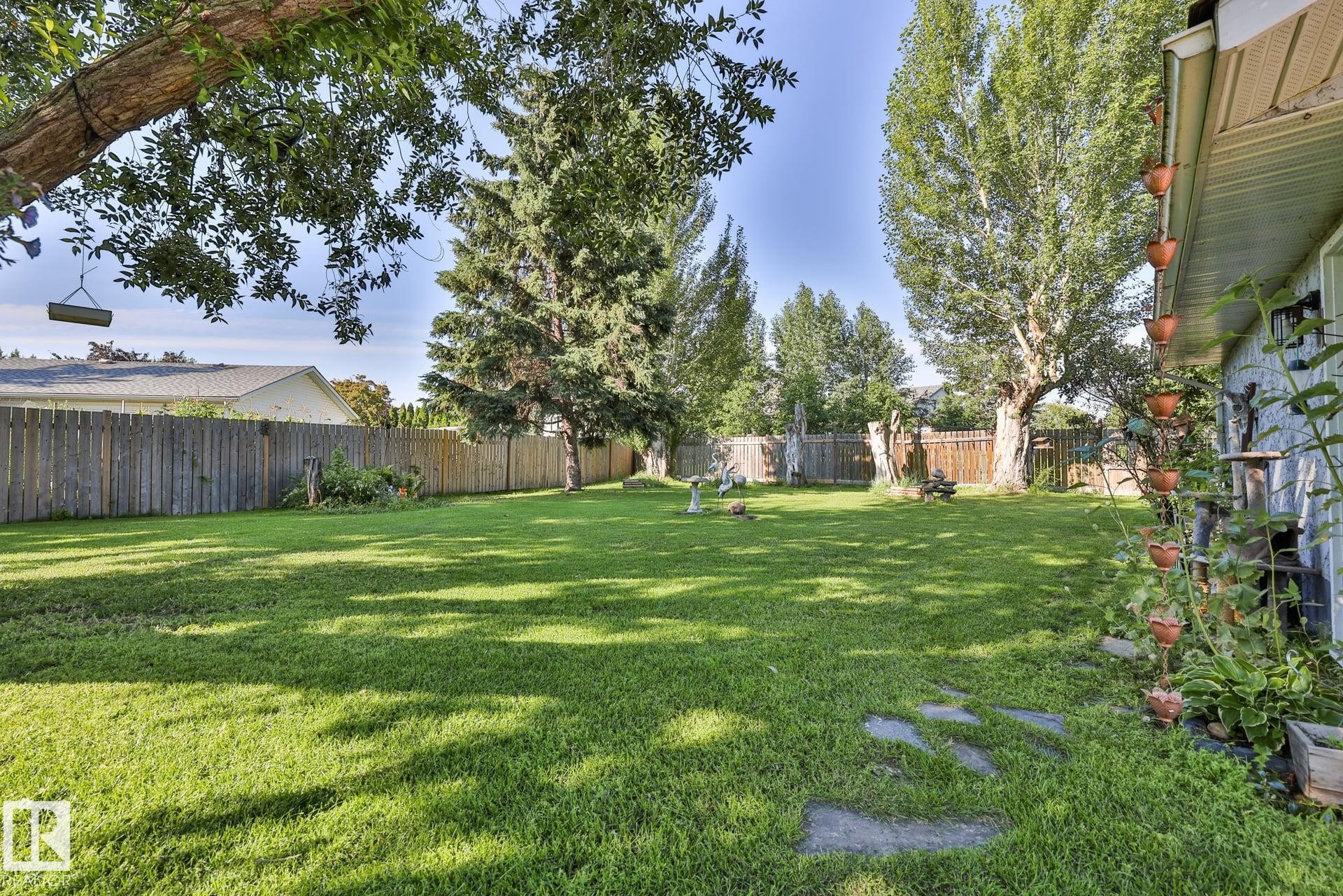 Expansive lawn area, mature trees, wood fence, and a stone pathway - 8932 187 Street Nw, Edmonton, AB - Outdoor With Backyard