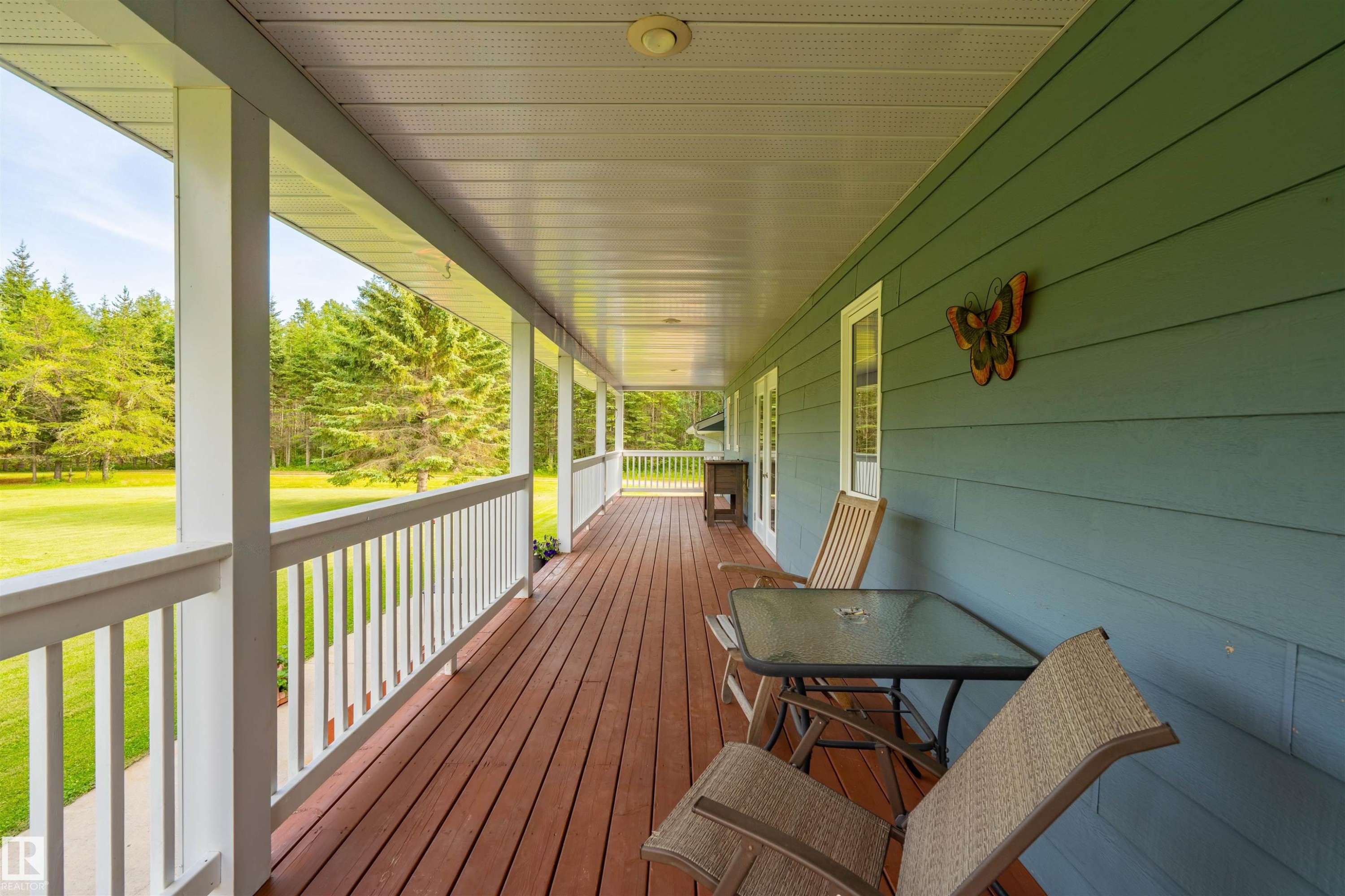 Expansive covered porch featuring wood-finish flooring and white railings - 59125 Range Road 102, Rural St. Paul County, AB - Outdoor With Deck Patio Veranda With Exterior