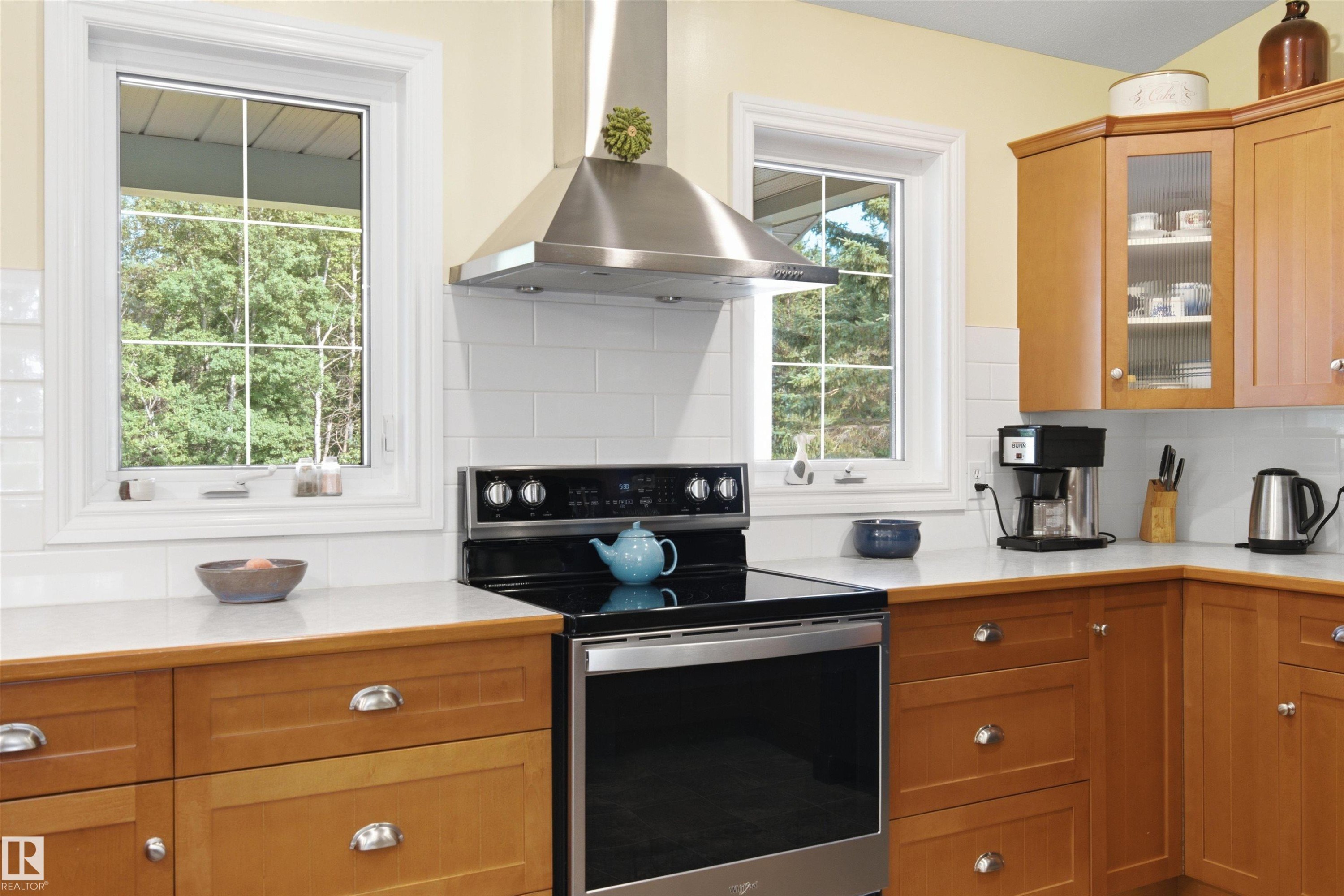 Modern kitchen featuring a stainless steel range with matching hood, subway tile backsplash, light wood cabinetry - 59125 Range Road 102, Rural St. Paul County, AB - Indoor Photo Showing Kitchen