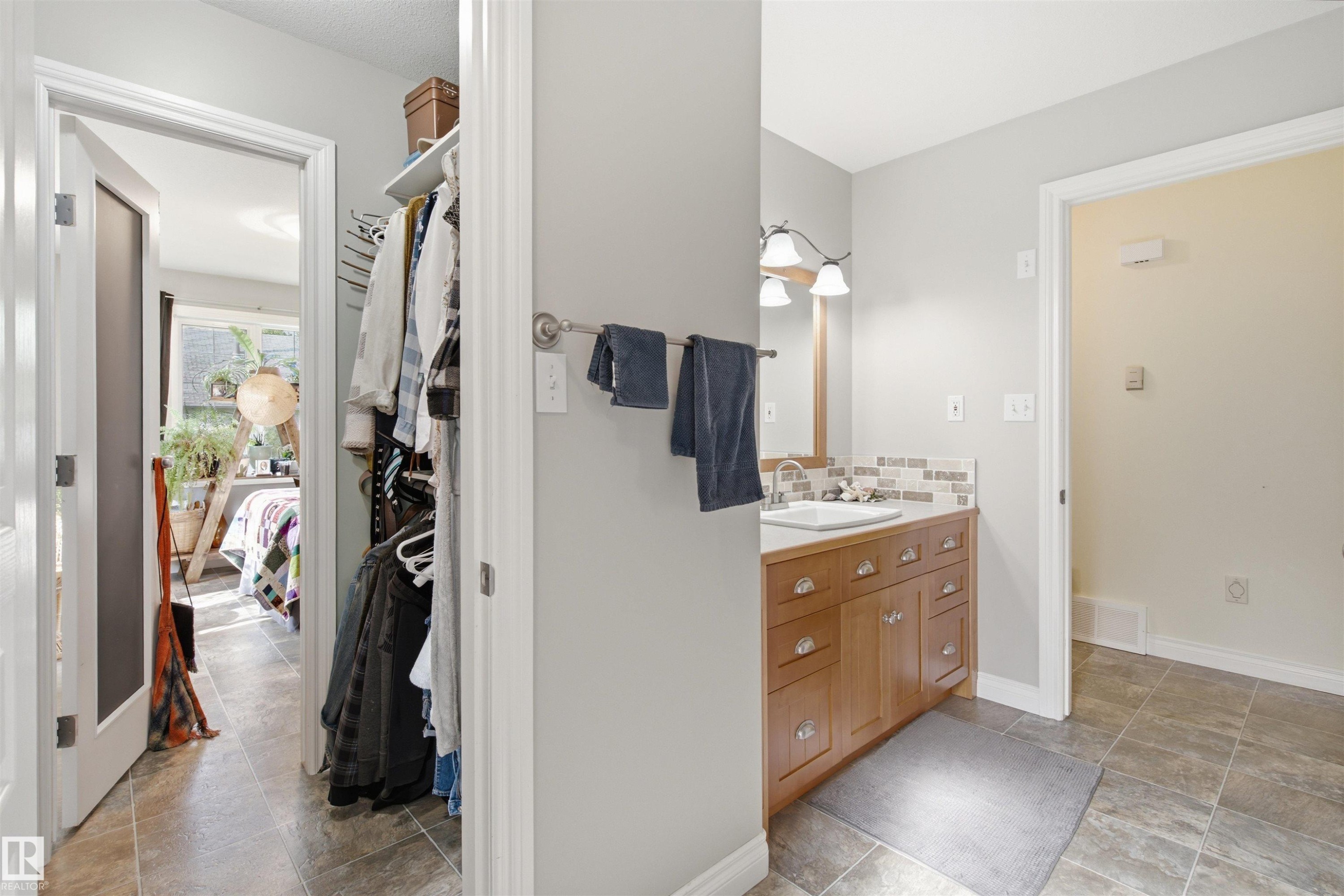 Bathroom vanity featuring a light wood-finish cabinet with multiple drawers and doors, a white rectangular sink, and a multi-toned mosaic tile backsplash - 59125 Range Road 102, Rural St. Paul County, AB - Indoor Photo Showing Bathroom