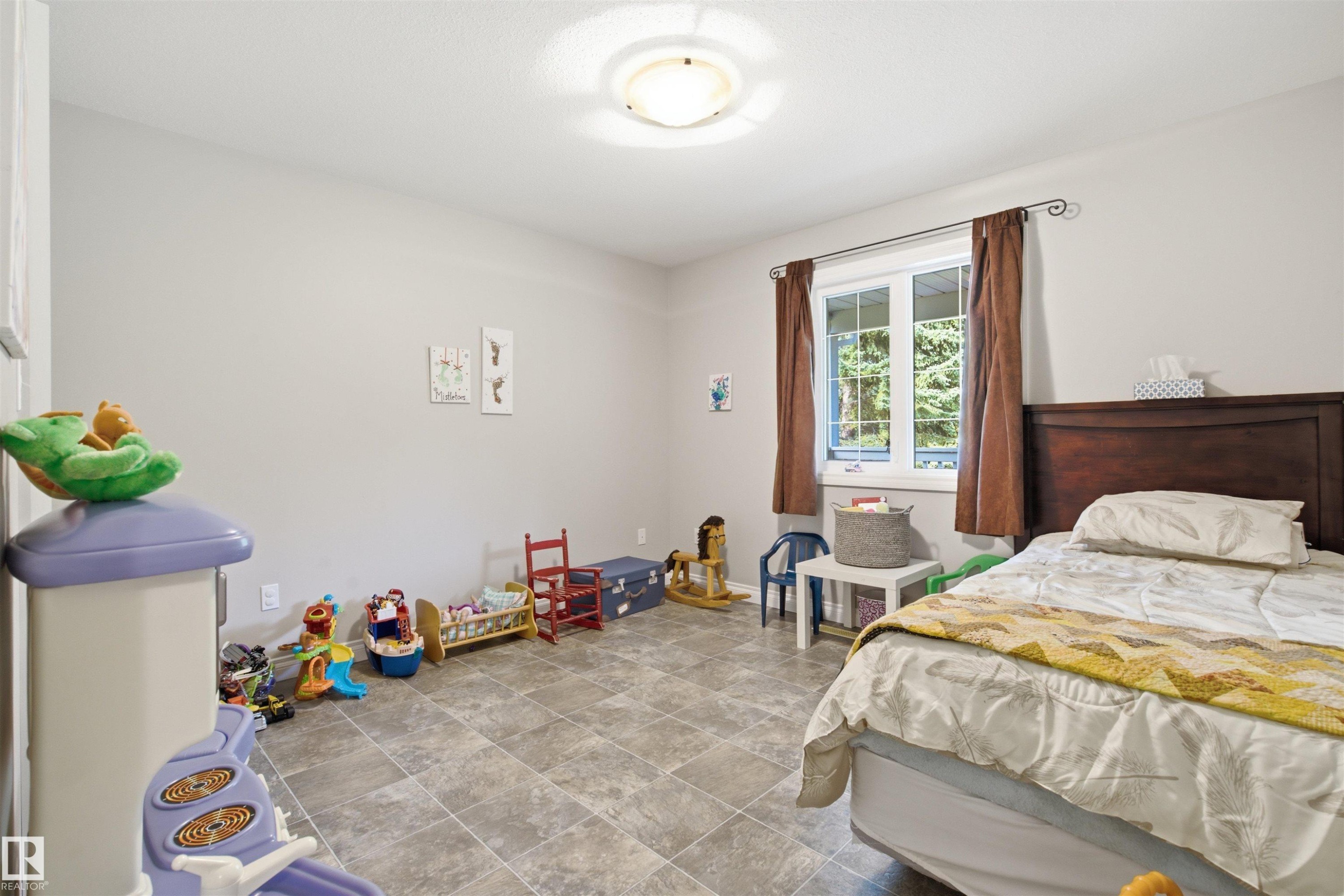Spacious room featuring neutral tone walls, a large window with exterior tree views - 59125 Range Road 102, Rural St. Paul County, AB - Indoor Photo Showing Bedroom