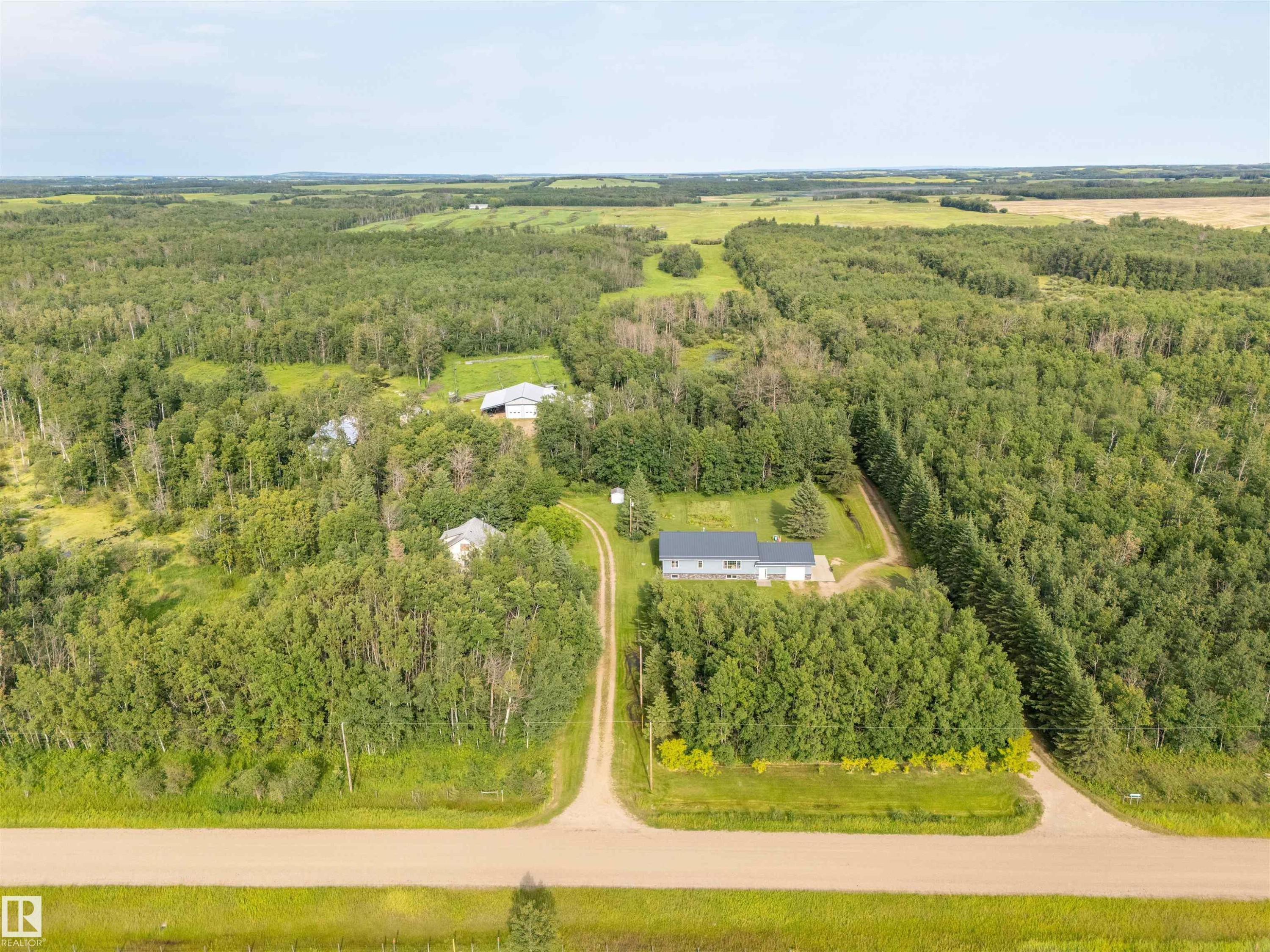 Expansive rural property featuring multiple structures, verdant treelines, and a gravel driveway system - 59125 Range Road 102, Rural St. Paul County, AB - Outdoor With View
