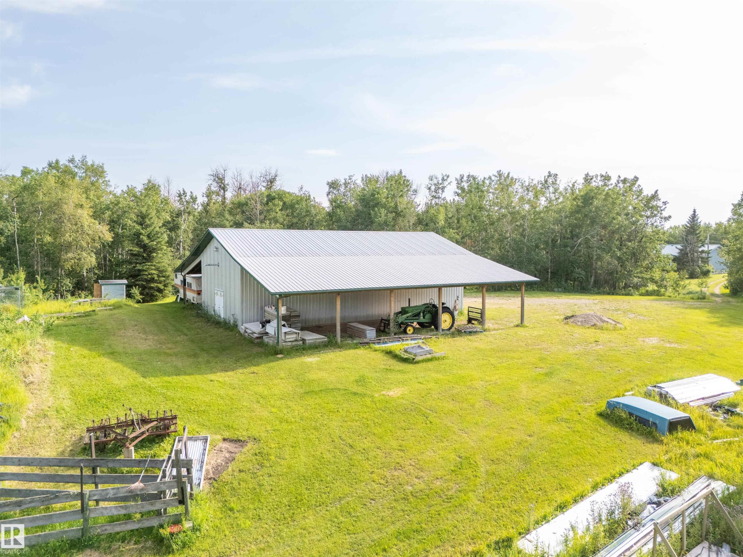 Spacious metal-sided outbuilding with a corrugated metal roof and an open-sided covered area - 59125 Range Road 102, Rural St. Paul County, AB - Outdoor With Deck Patio Veranda