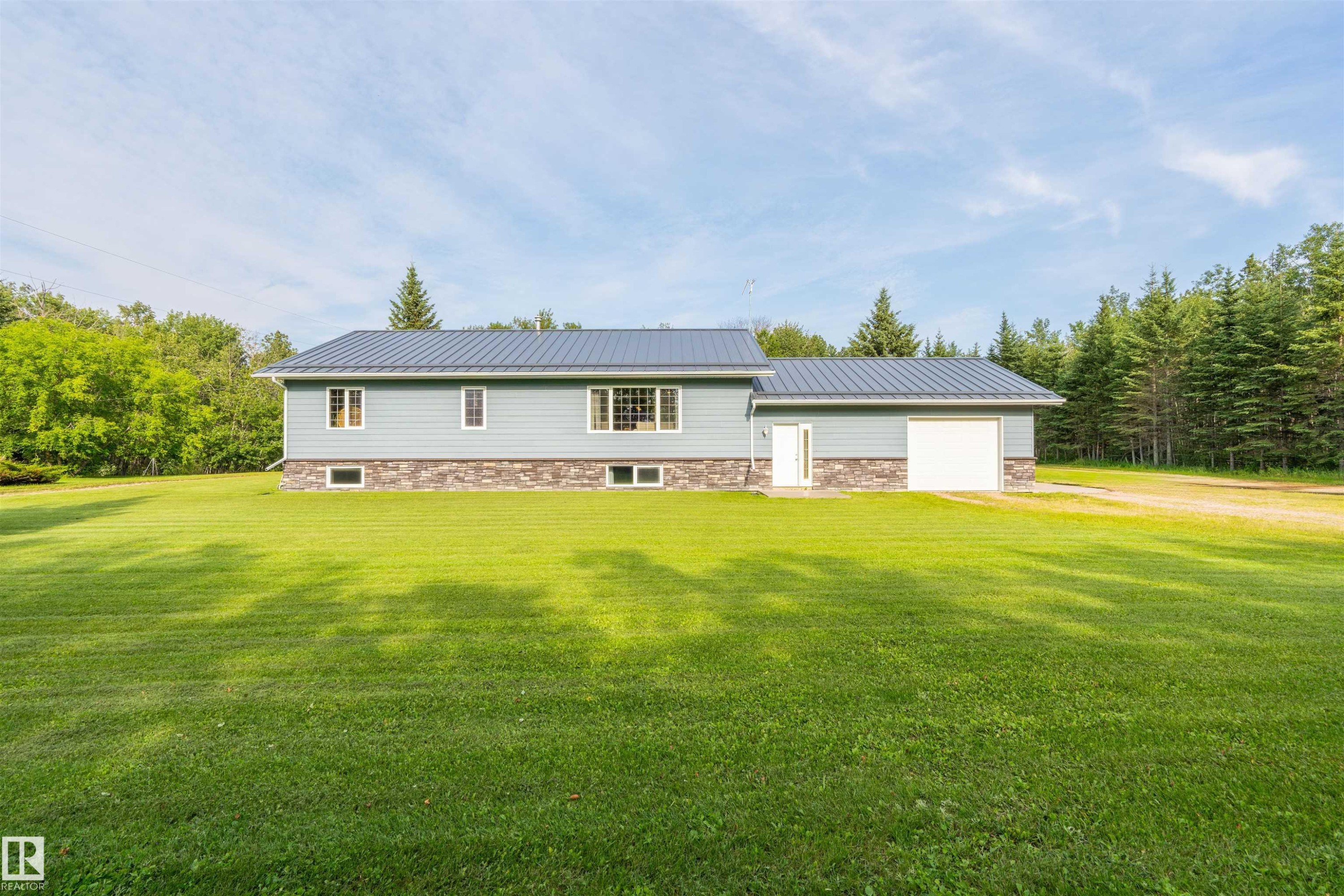 Residential property featuring light blue siding with a stone-finish foundation - 59125 Range Road 102, Rural St. Paul County, AB - Outdoor