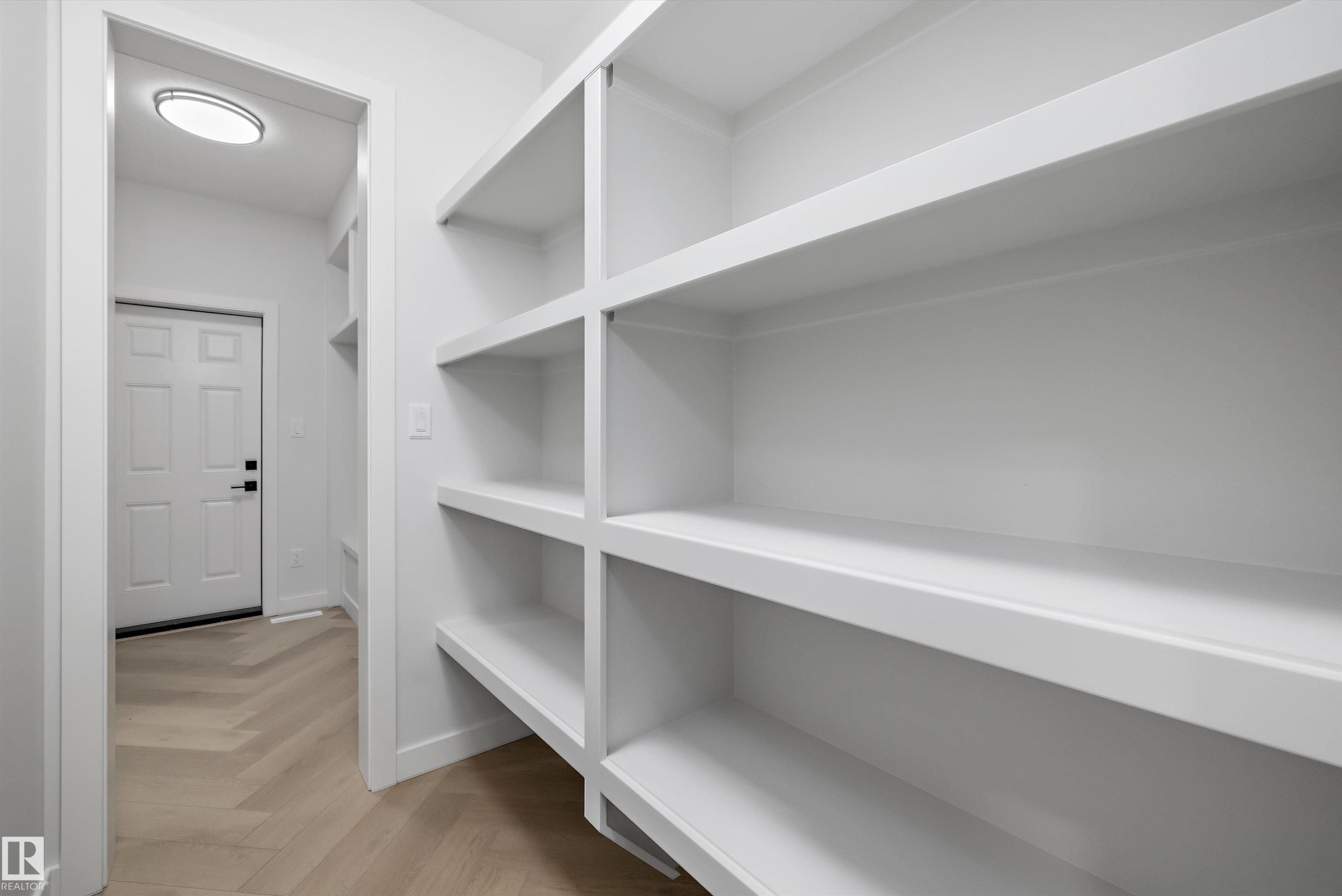 Built-in white shelving, recessed lighting, and wood-finish herringbone flooring - 971 Elderberry Landing Nw, Edmonton, AB - Indoor With Storage