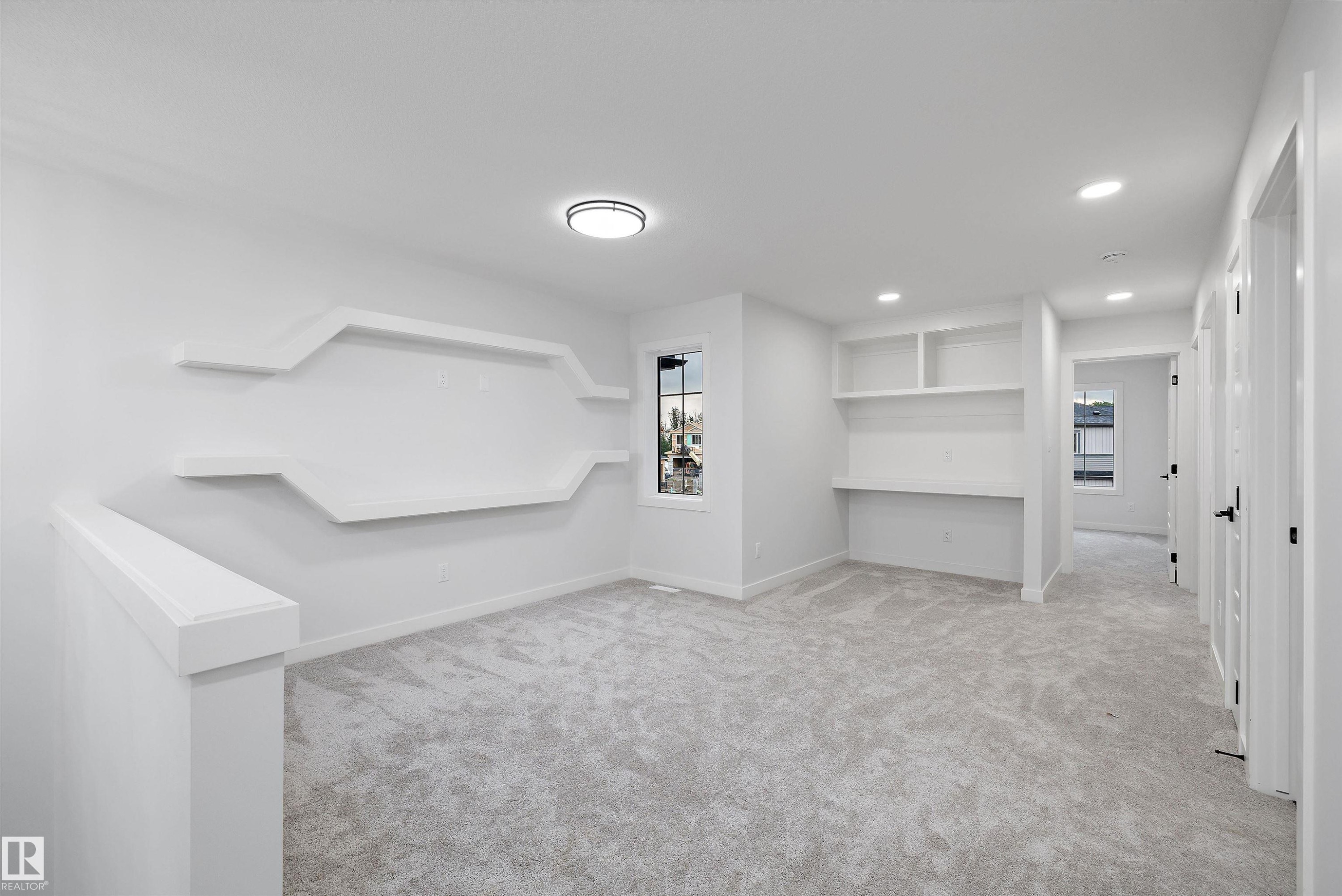 Neutral-toned carpeting throughout with built-in shelving, a dedicated desk area, and recessed lighting - 971 Elderberry Landing Nw, Edmonton, AB - Indoor Photo Showing Other Room