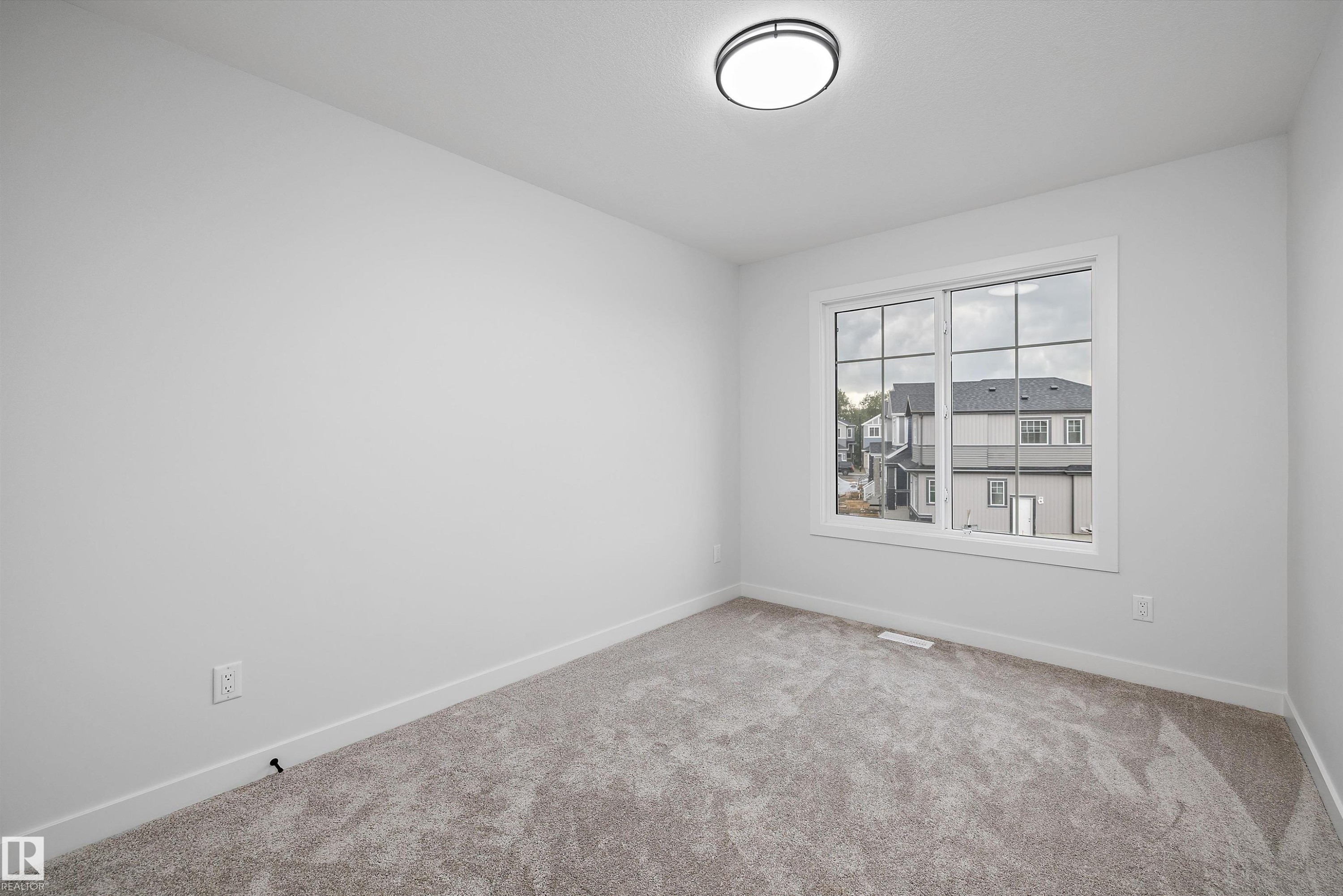 Bright room featuring neutral wall paint, a large window with white framing, and gray carpet flooring - 971 Elderberry Landing Nw, Edmonton, AB - Indoor Photo Showing Other Room