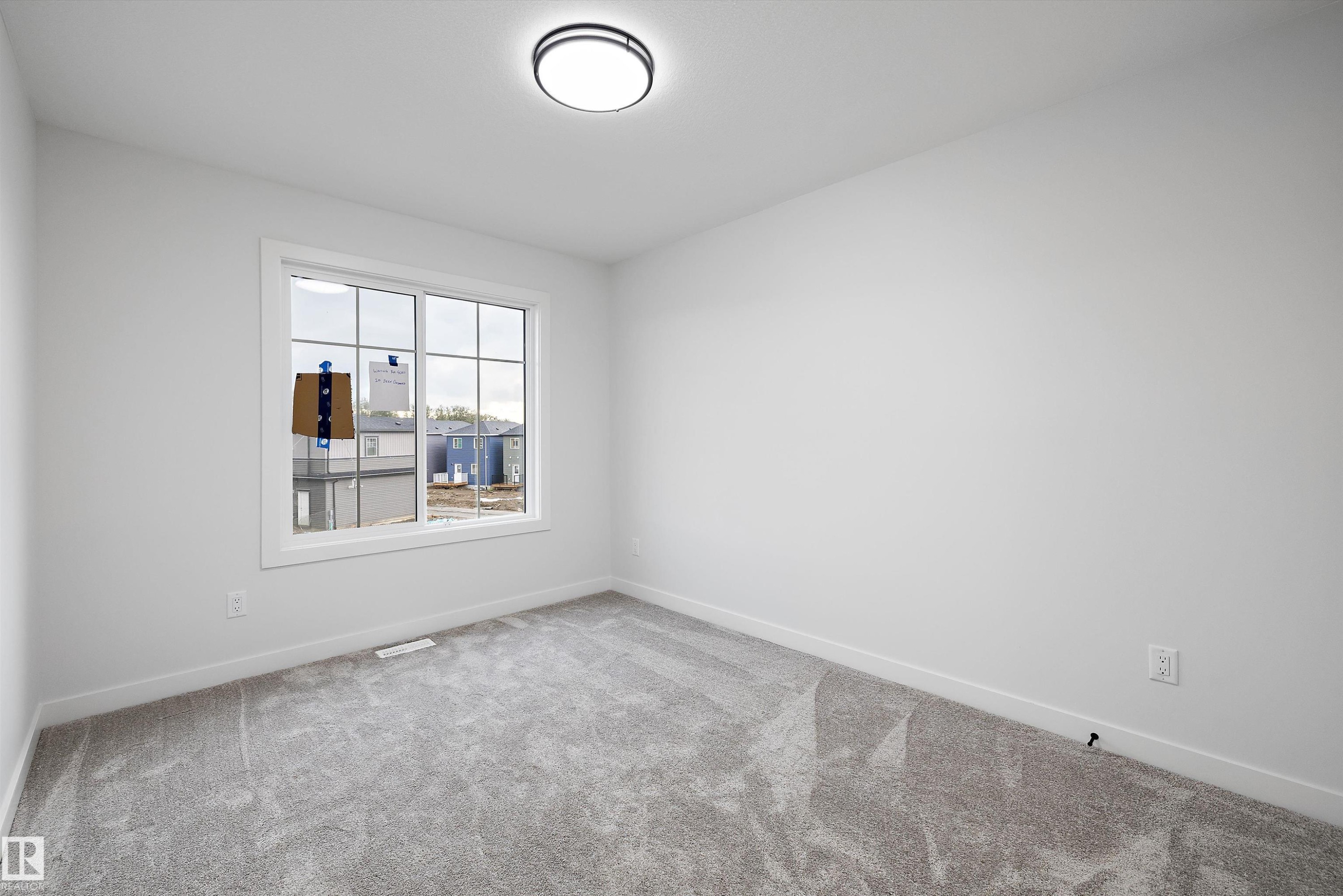 Neutral color palette, window with grid, flush-mount ceiling light, carpeted flooring, and white trim - 971 Elderberry Landing Nw, Edmonton, AB - Indoor Photo Showing Other Room