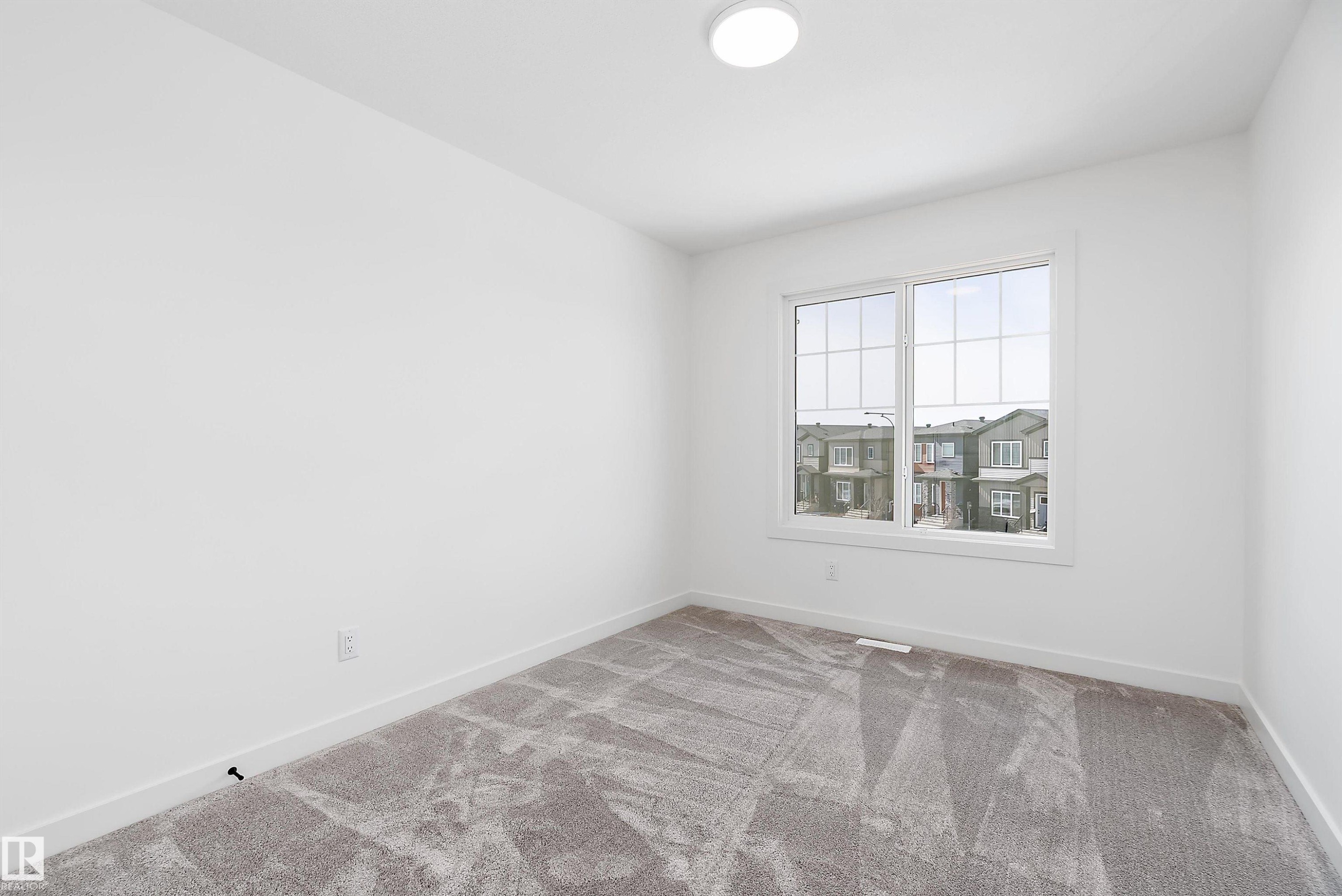 Recessed lighting, large window with multi-pane grid, plush carpeting, light-toned walls, and white trim - 1763 Crossbill Loop Nw, Edmonton, AB - Indoor Photo Showing Other Room