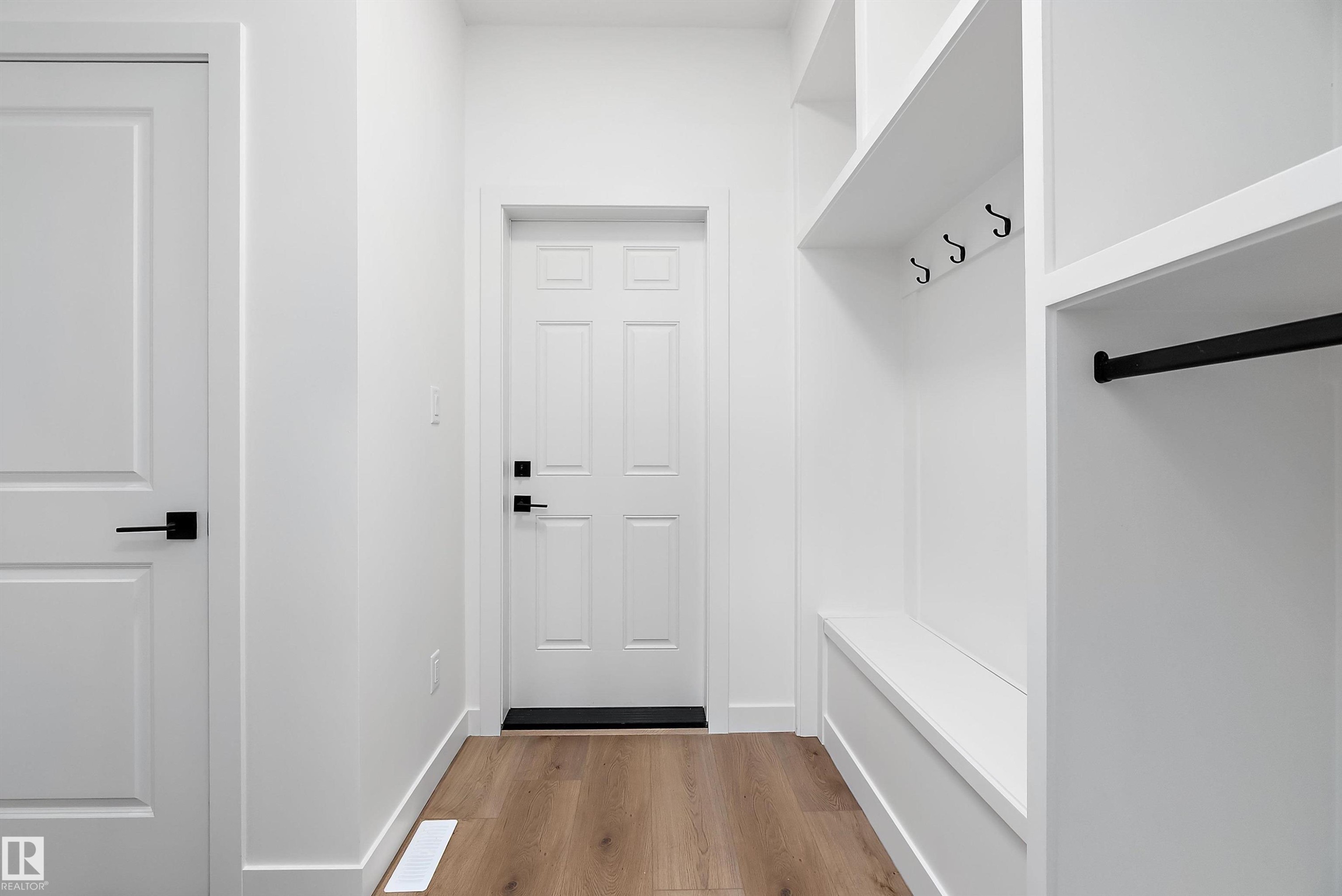 Built-in mudroom storage featuring open shelving, black coat hooks, and a bench - 1763 Crossbill Loop Nw, Edmonton, AB - Indoor Photo Showing Other Room