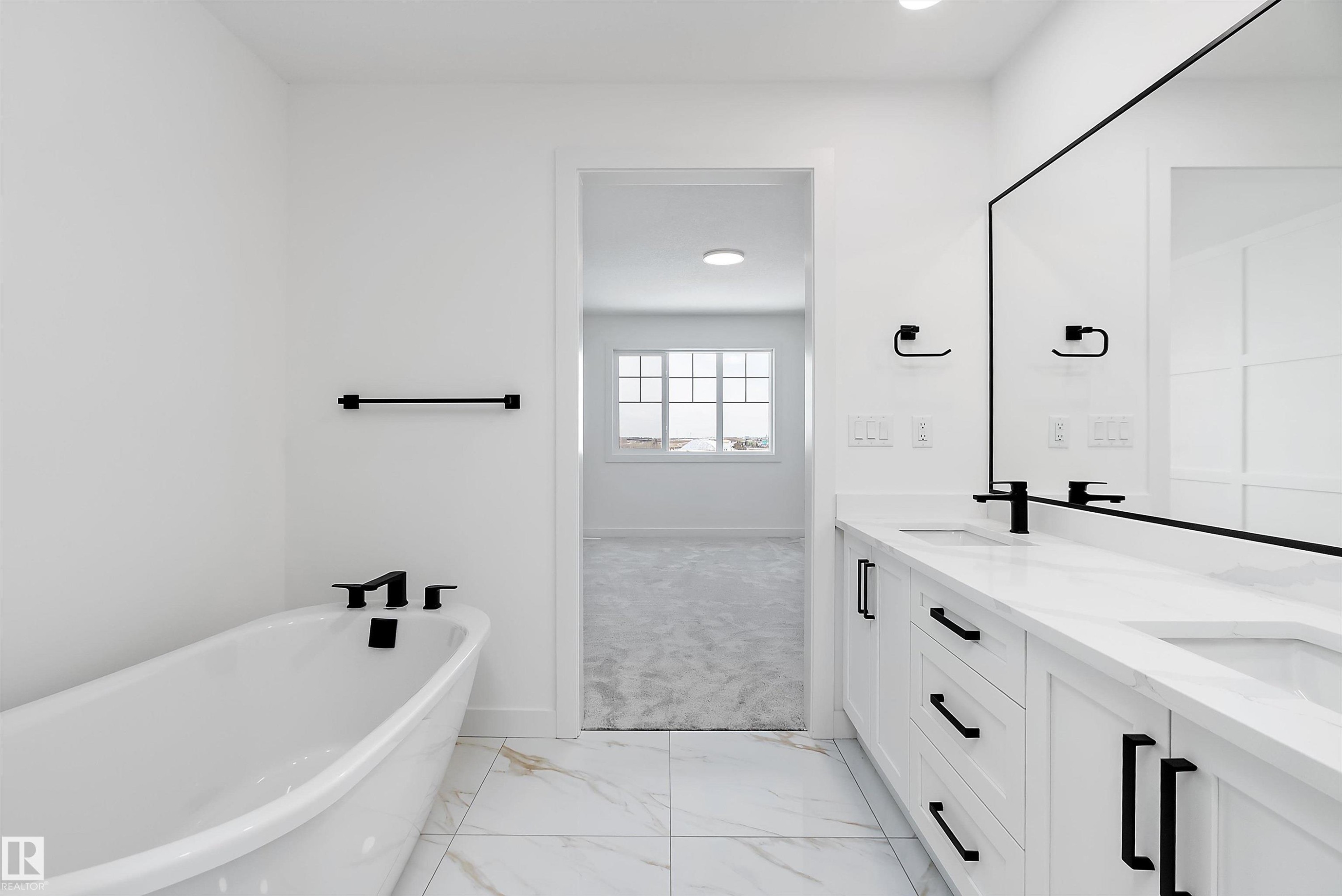 White vanity with dual sinks, black fixtures, and a freestanding bathtub - 1763 Crossbill Loop Nw, Edmonton, AB - Indoor Photo Showing Bathroom