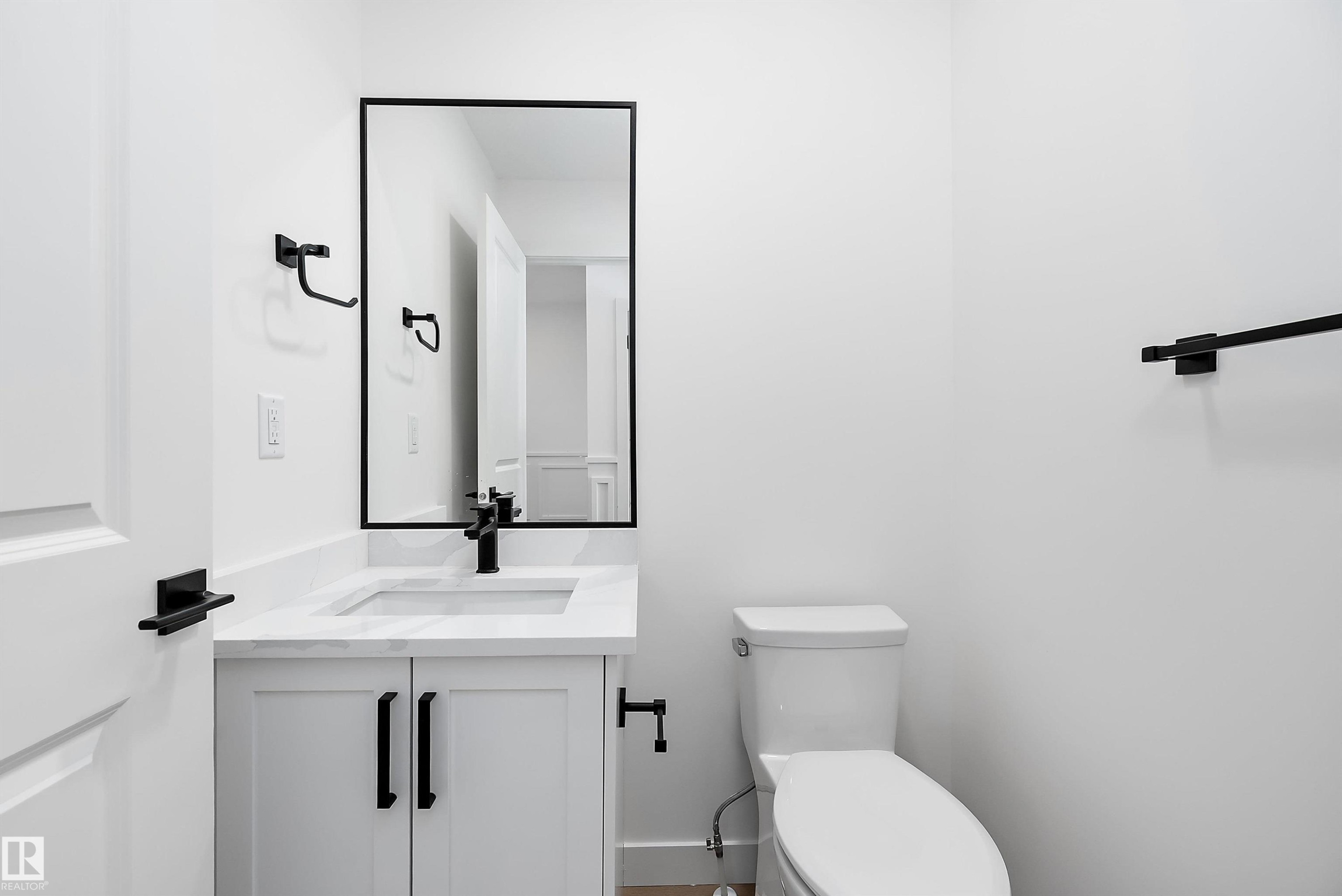 White vanity with matte black hardware, integrated rectangular sink, and stone-finish countertop - 1763 Crossbill Loop Nw, Edmonton, AB - Indoor Photo Showing Bathroom