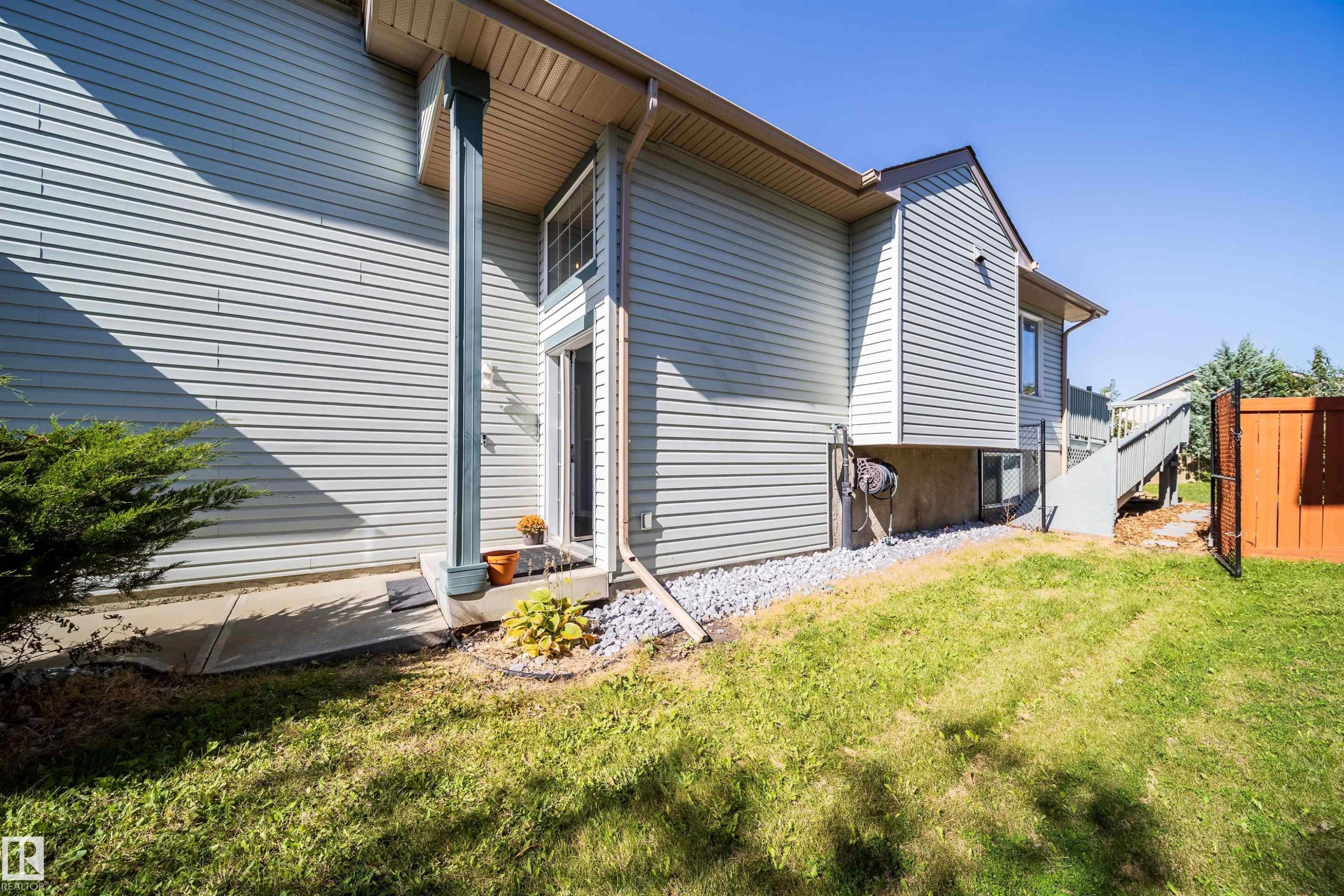 Siding exterior with a covered entry, concrete pathway, and gravel landscaping - 7848 7 Avenue Sw, Edmonton, AB