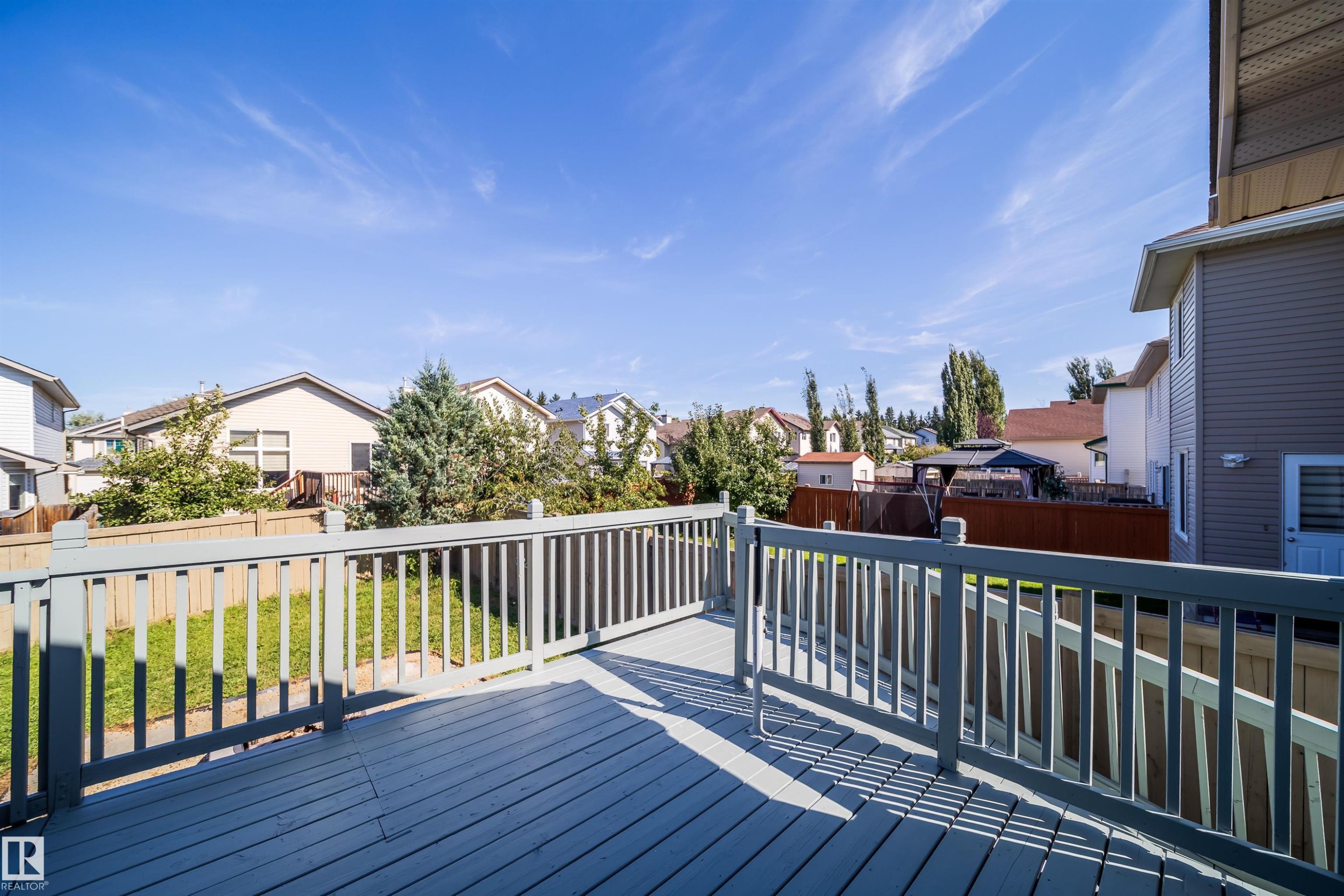 Expansive deck with painted wood-finish railing and decking - 7848 7 Avenue Sw, Edmonton, AB