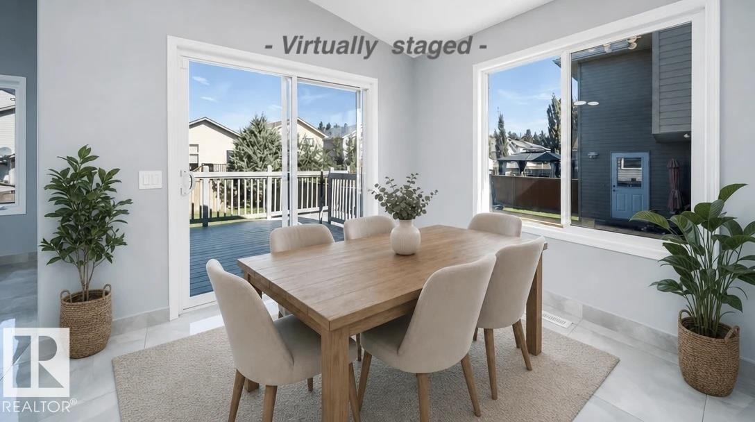 Sliding glass door leading to a wood-finish deck, bright windows, and tile flooring - 7848 7 Avenue Sw, Edmonton, AB