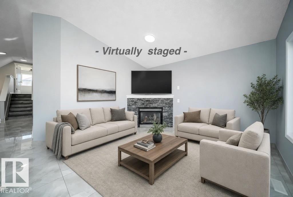 Vaulted ceiling with recessed lighting, stone-clad fireplace, built-in media cabinet, large format tile flooring, and a two-story staircase with white risers - 7848 7 Avenue Sw, Edmonton, AB