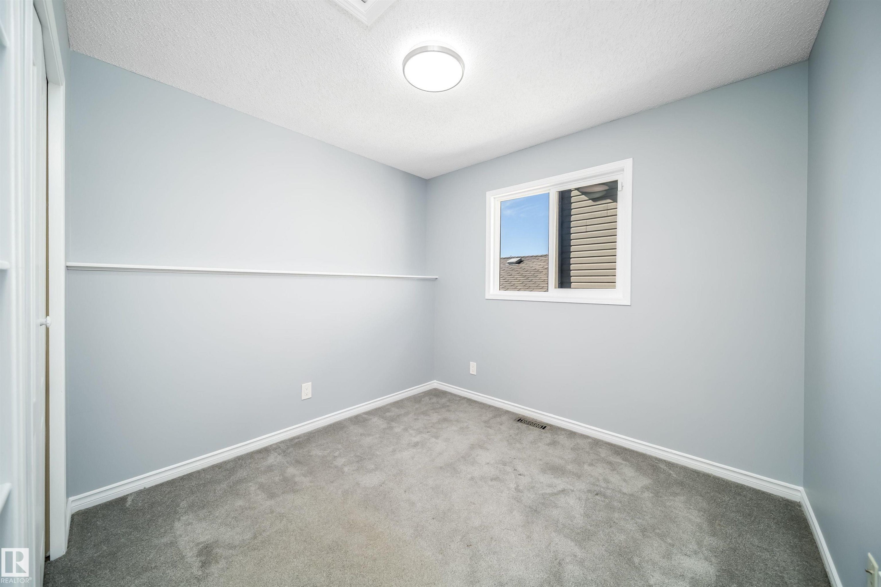 Light gray painted walls, a single window, and plush gray carpeting - 7848 7 Avenue Sw, Edmonton, AB
