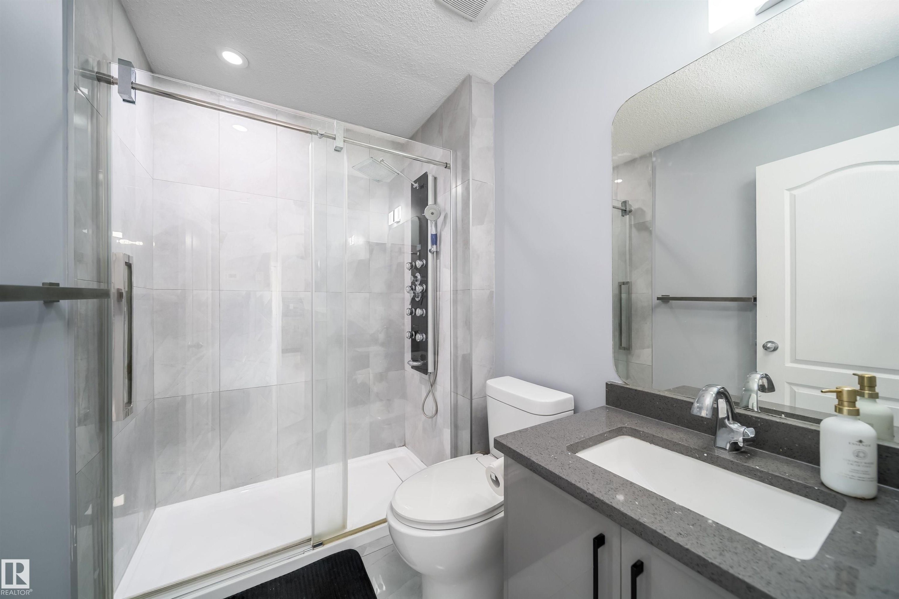 Walk-in shower with full-height tile surround, glass enclosure, and multi-function shower panel - 7848 7 Avenue Sw, Edmonton, AB